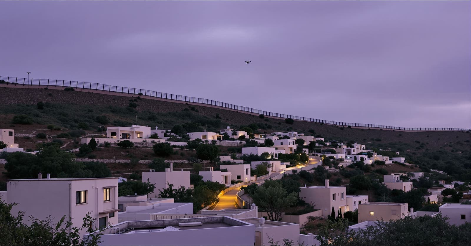 Illustration of a hillside village of pale stone houses near a border fence in Western Galilee at dusk, with a small drone shape in the sky.