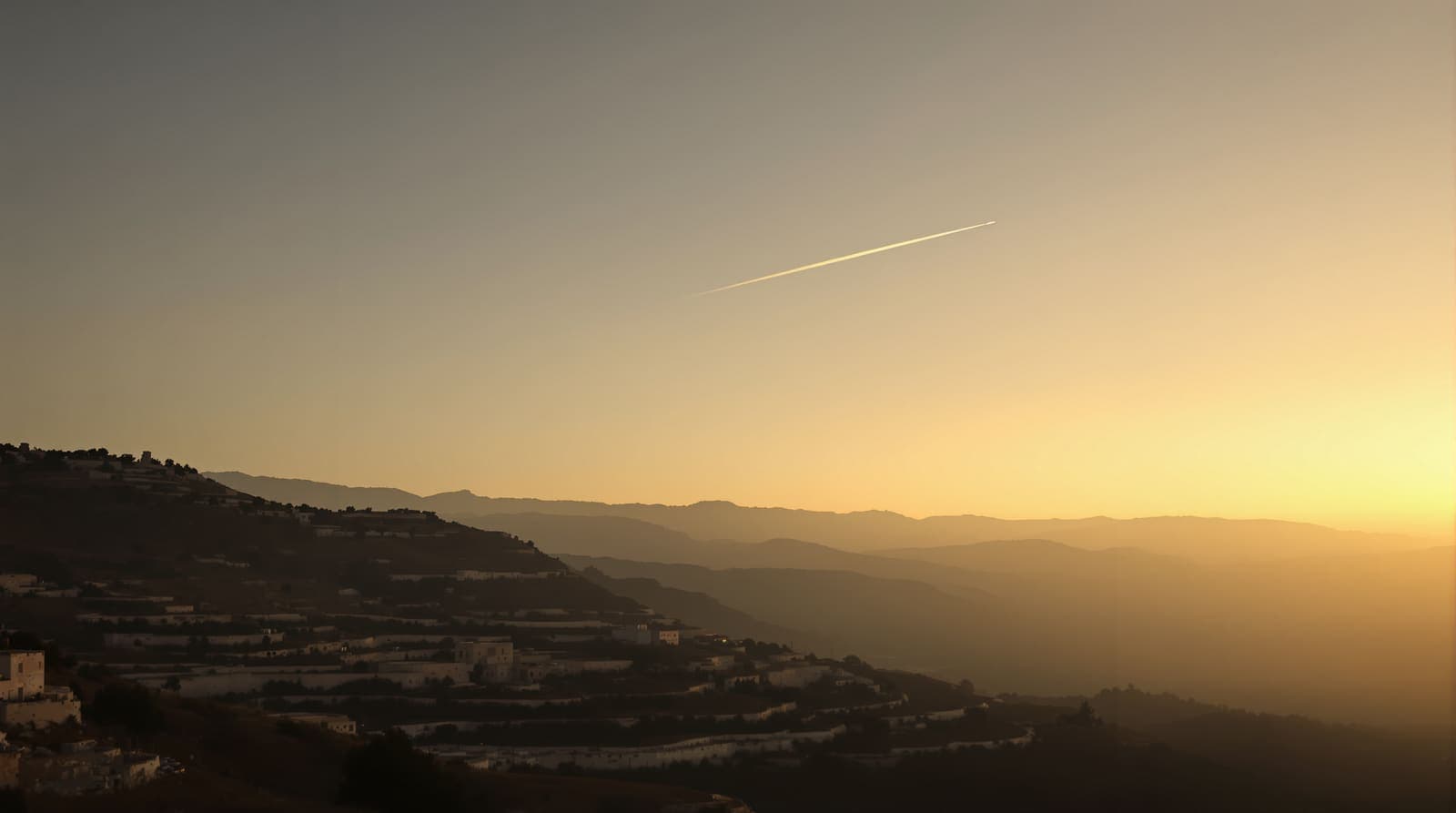 Illustration of a distant hillside skyline in southern Lebanon at dusk with a faint contrail arcing overhead.