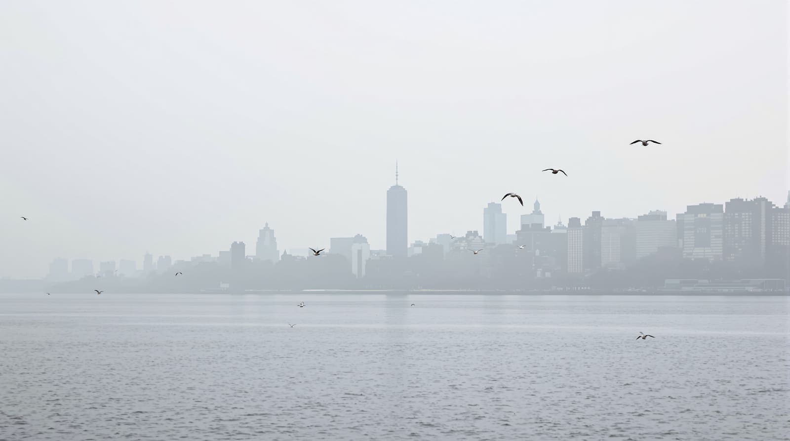 Illustration of the East River at dawn, with the distant Manhattan waterfront and a slim tower slab hazed in the skyline across the water.