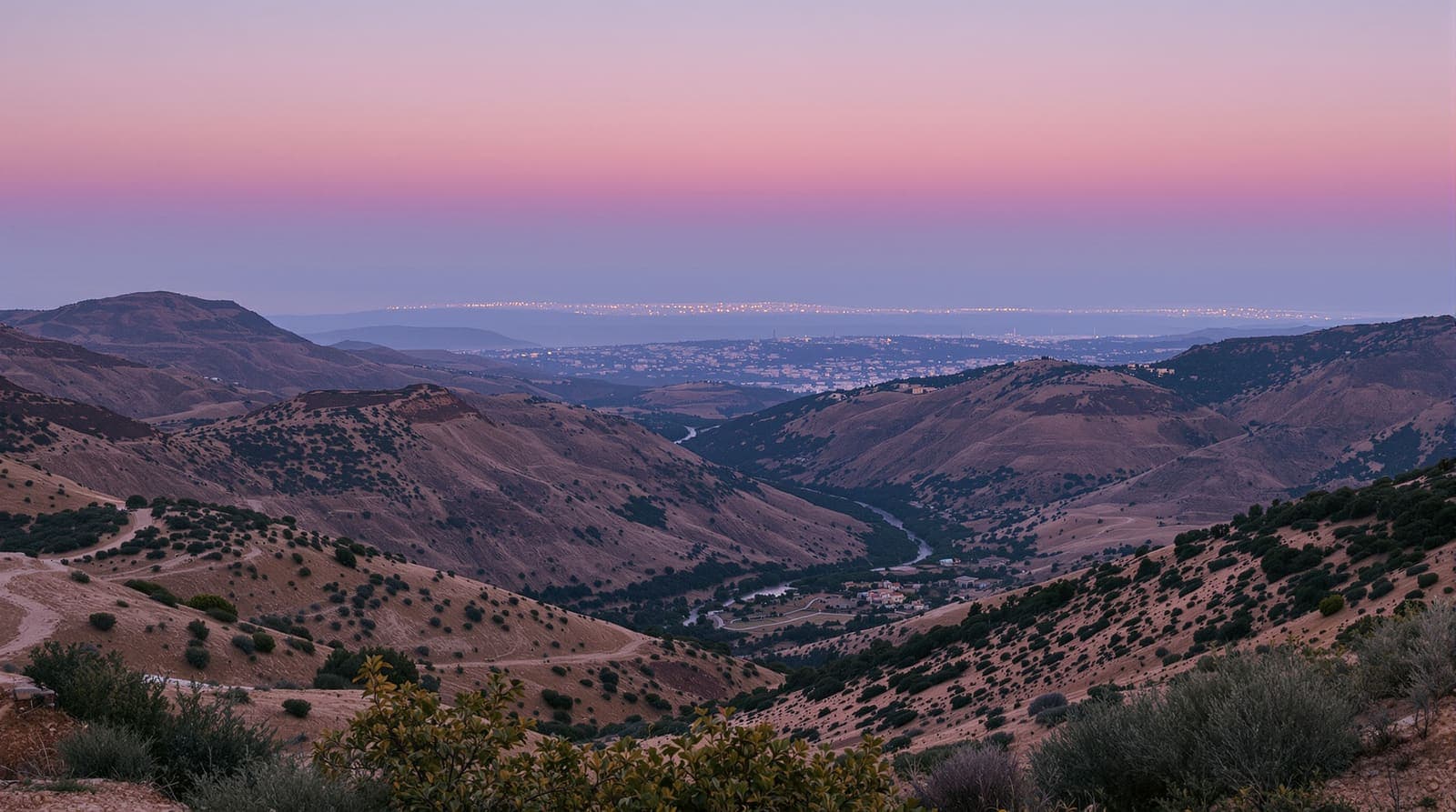 Illustration of the terraced hills, wadi and distant stone villages of southern Lebanon at dusk, with the coast beyond.