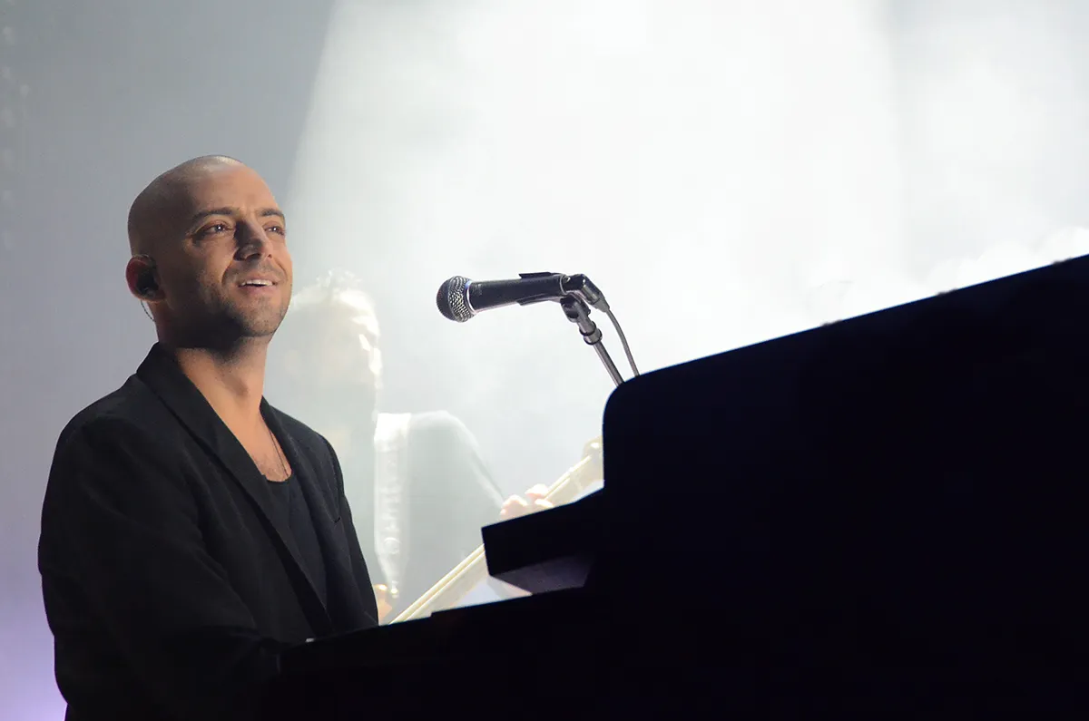 Idan Raichel smiling at the piano on stage, 2014