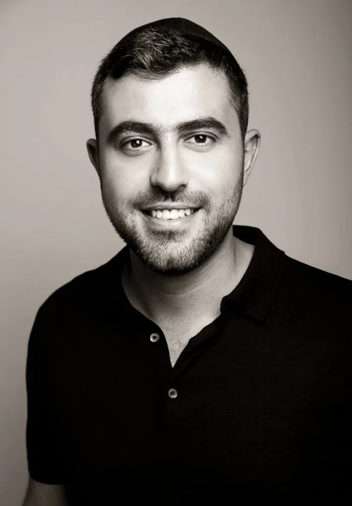 Ishay Ribo smiling in a black polo shirt, a black and white portrait, 2019