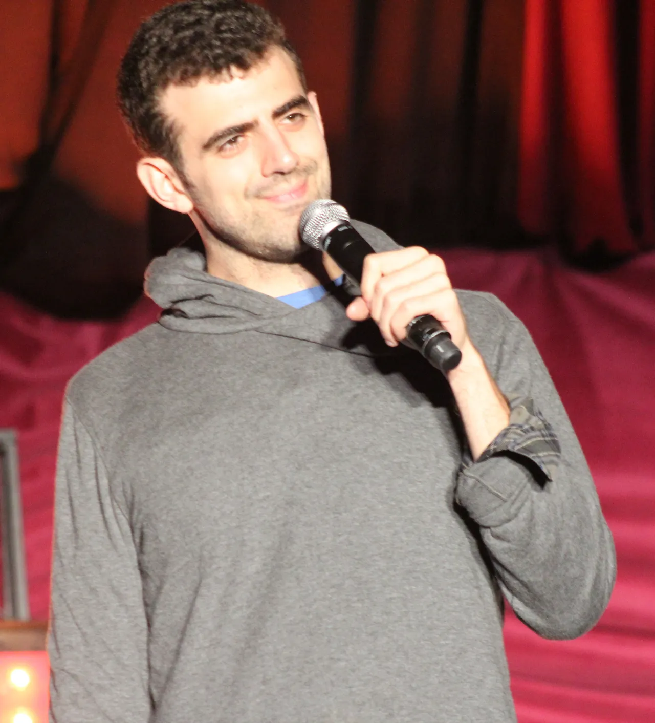 Sam Morril smiling with a microphone on stage at the Outside Lands festival in San Francisco, 2017