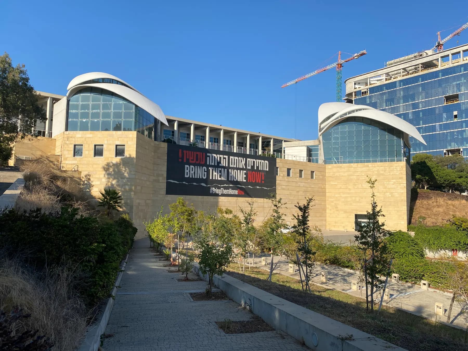 The stone building of the Yitzhak Rabin Center with its curved glass roofs, a banner on its wall