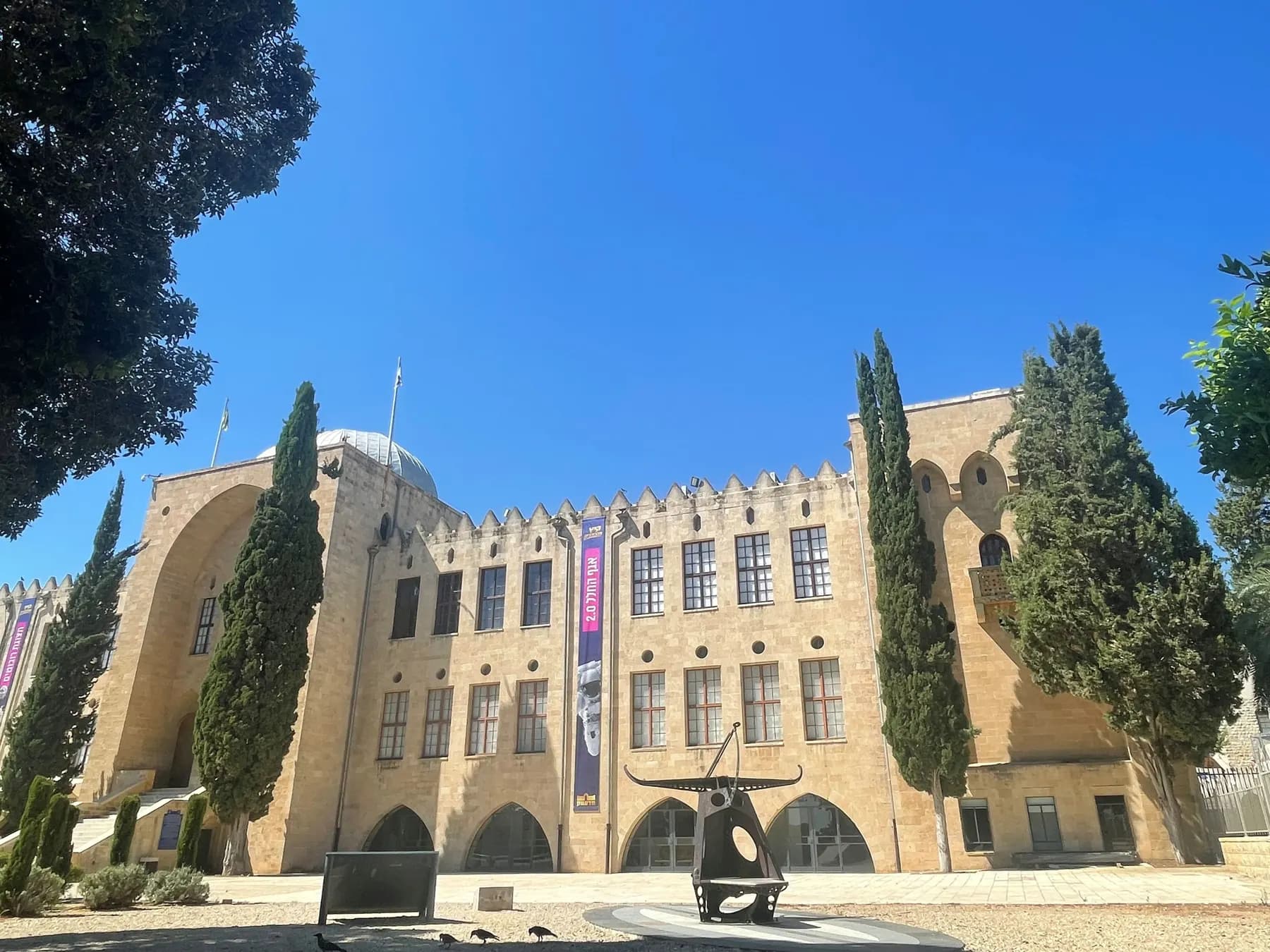 The Madatech building, the old Technion's stone building with its towers, among cypress trees