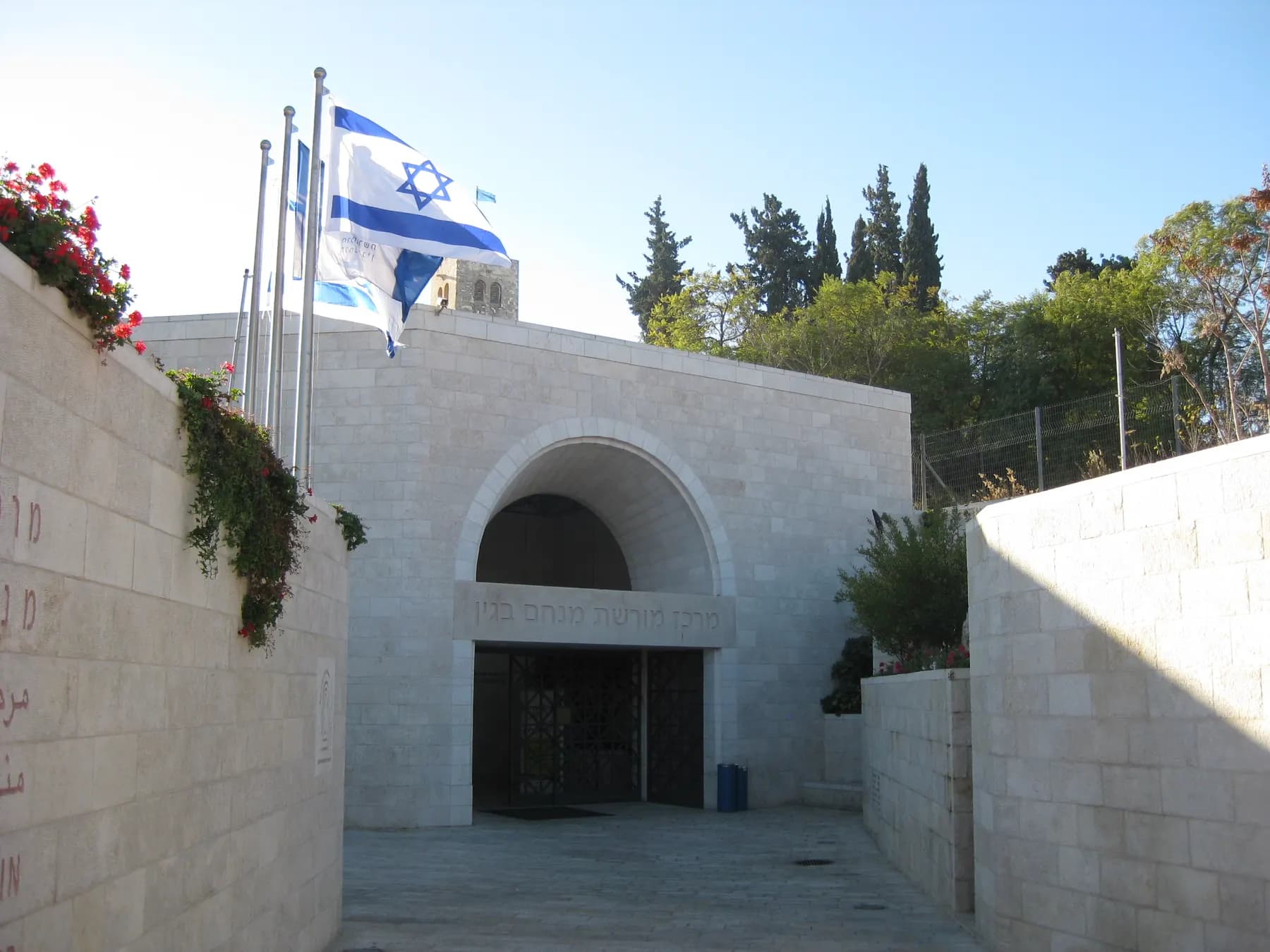 The arched stone entrance of the Menachem Begin Heritage Center, with flags above it