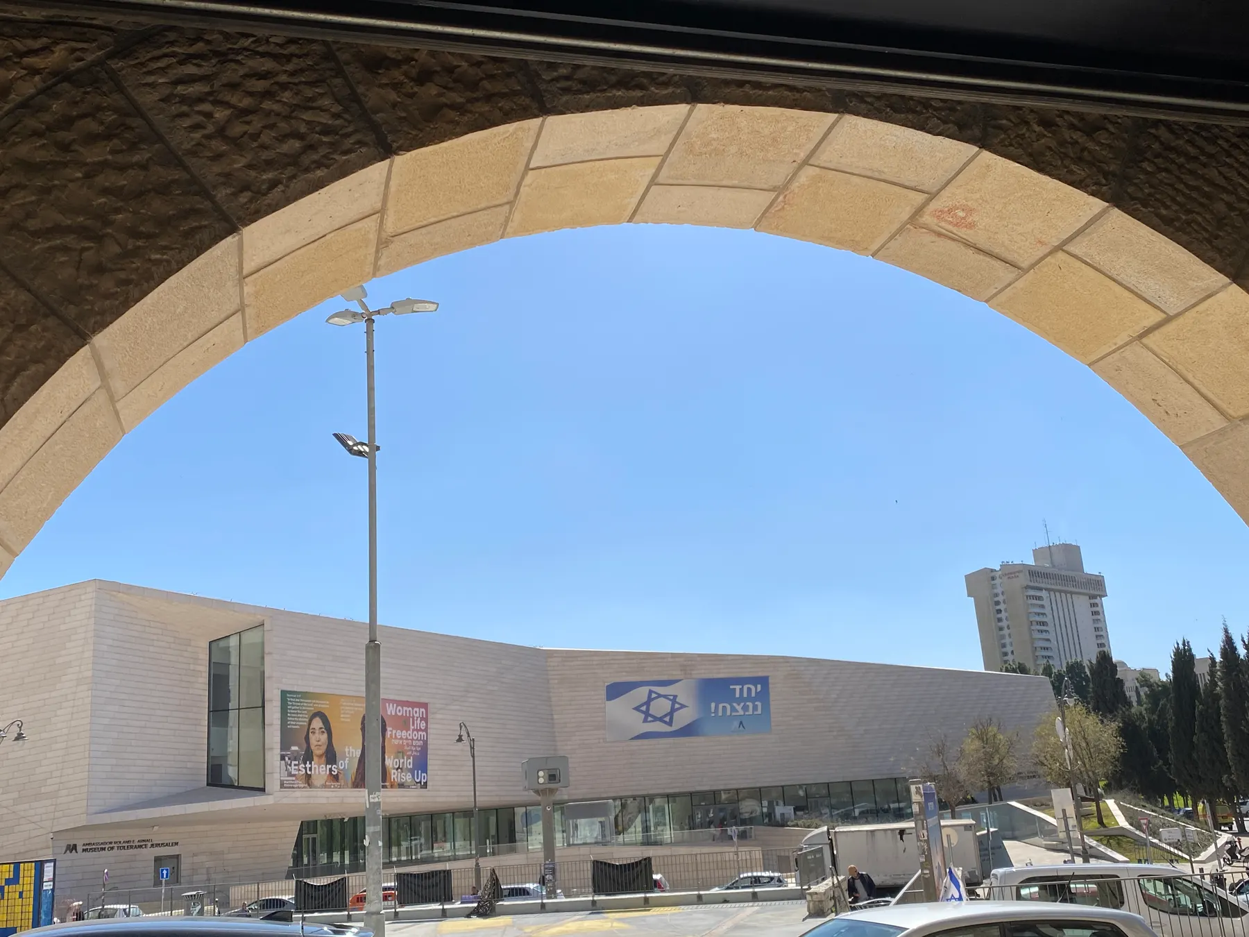 The long, low building of the Museum of Tolerance seen through a stone arch