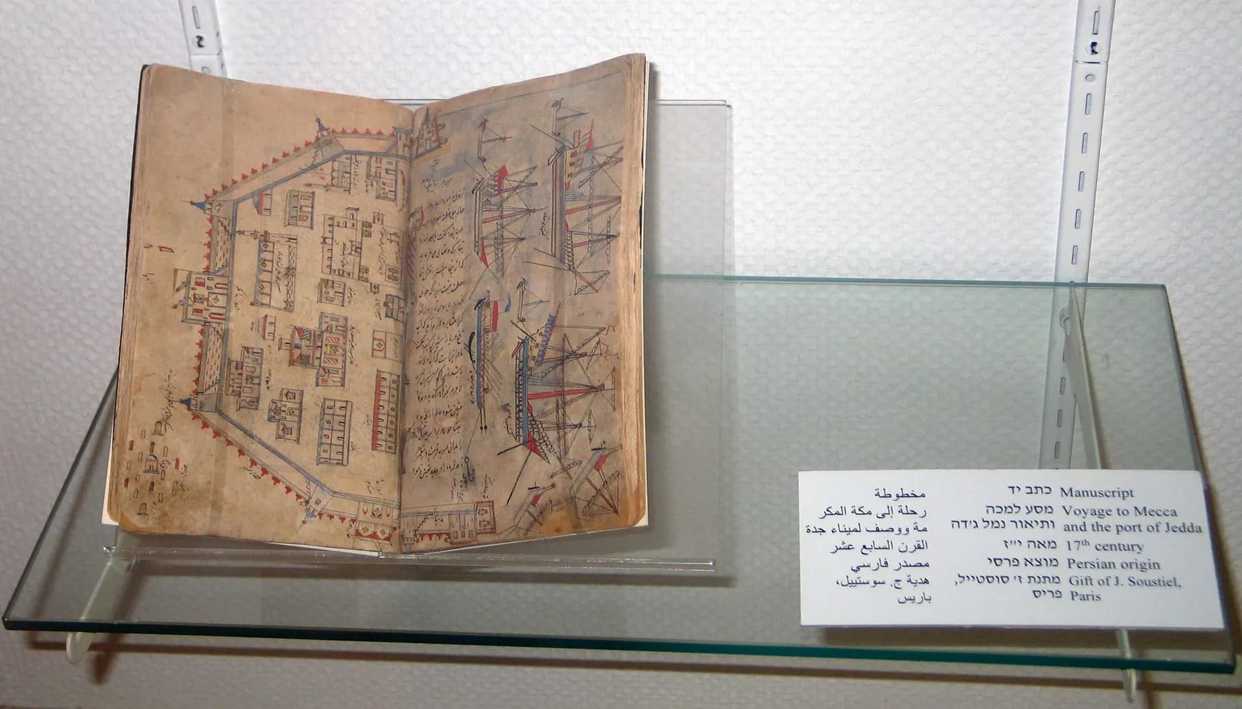 An old handwritten book of maps open in a glass case at the National Maritime Museum