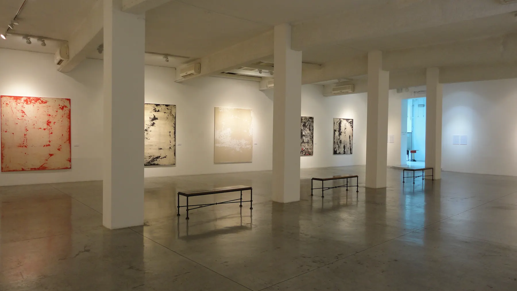 A gallery hall at the Museum of Israeli Art in Ramat Gan, with paintings on white walls between pillars