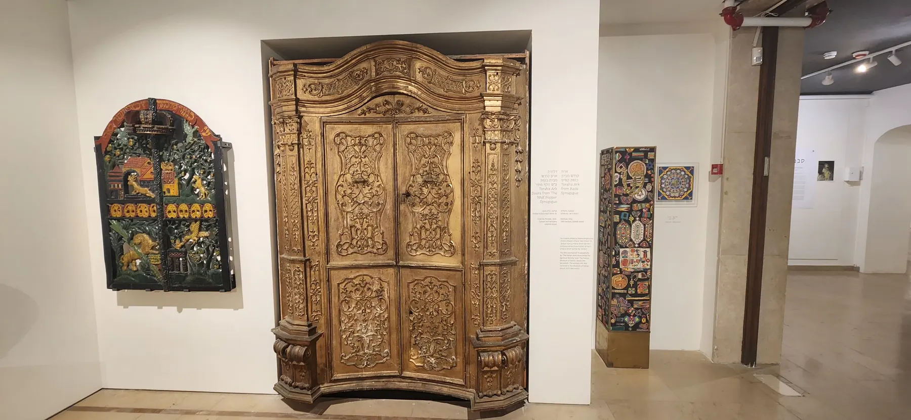 A gallery of the Wolfson Museum, with a carved and gilded Torah ark and a painted ark door on its walls