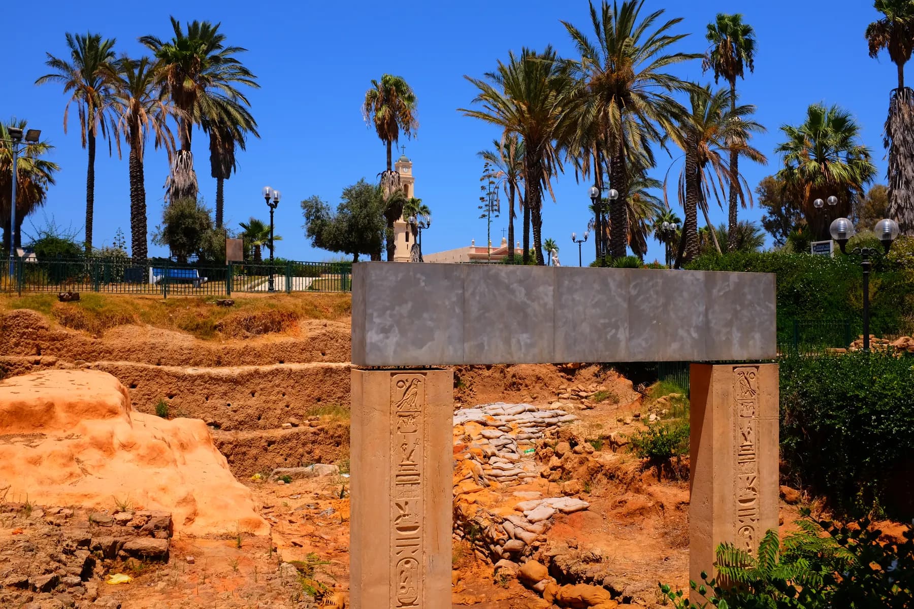 The reconstructed jambs of the Ramses II gate, carved with hieroglyphs and carrying a plain concrete lintel, standing over a stone threshold in the excavated garden below the Jaffa hill