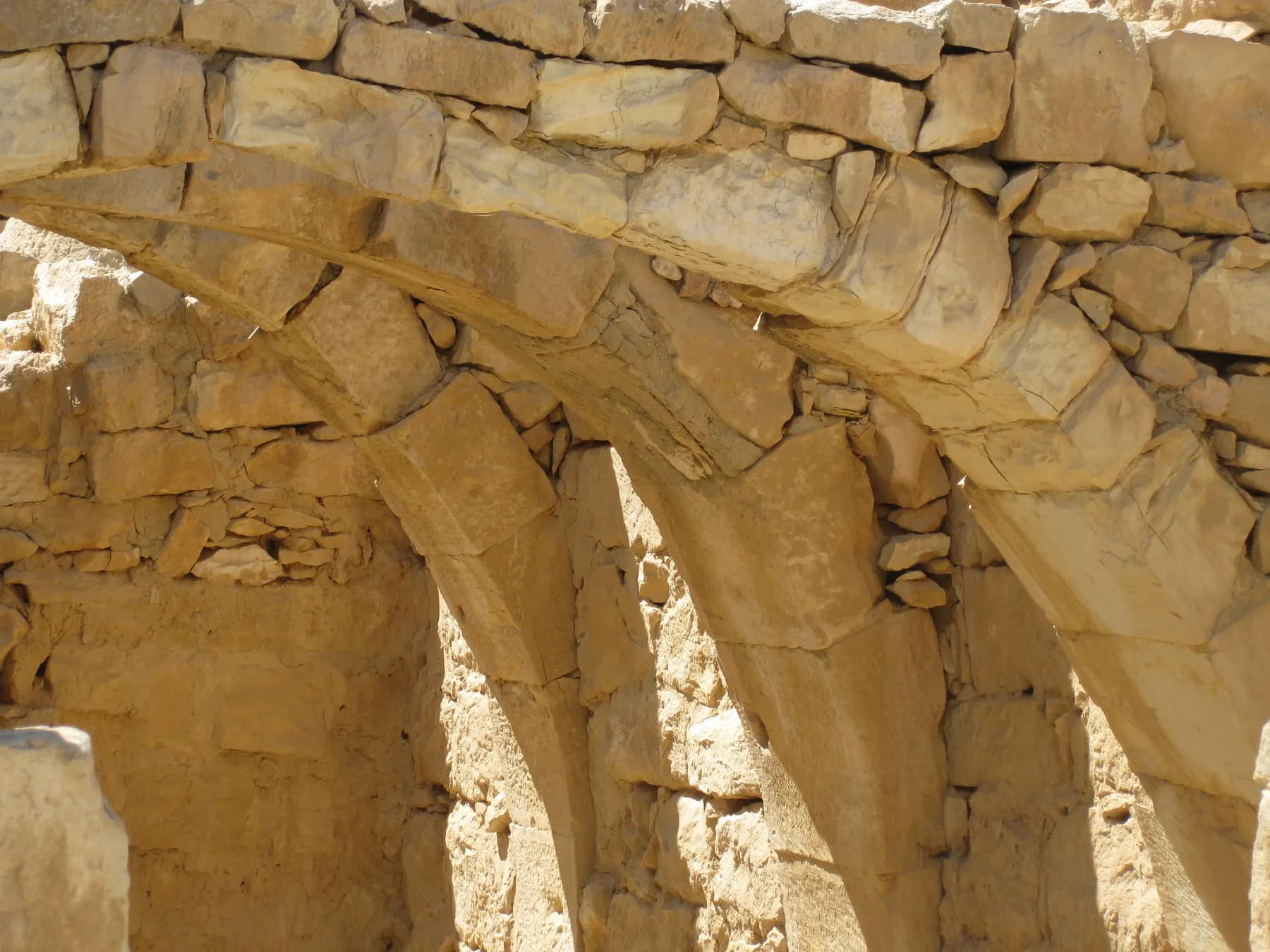 Sunlit stone arches springing from the masonry walls of a ruined house at Mamshit