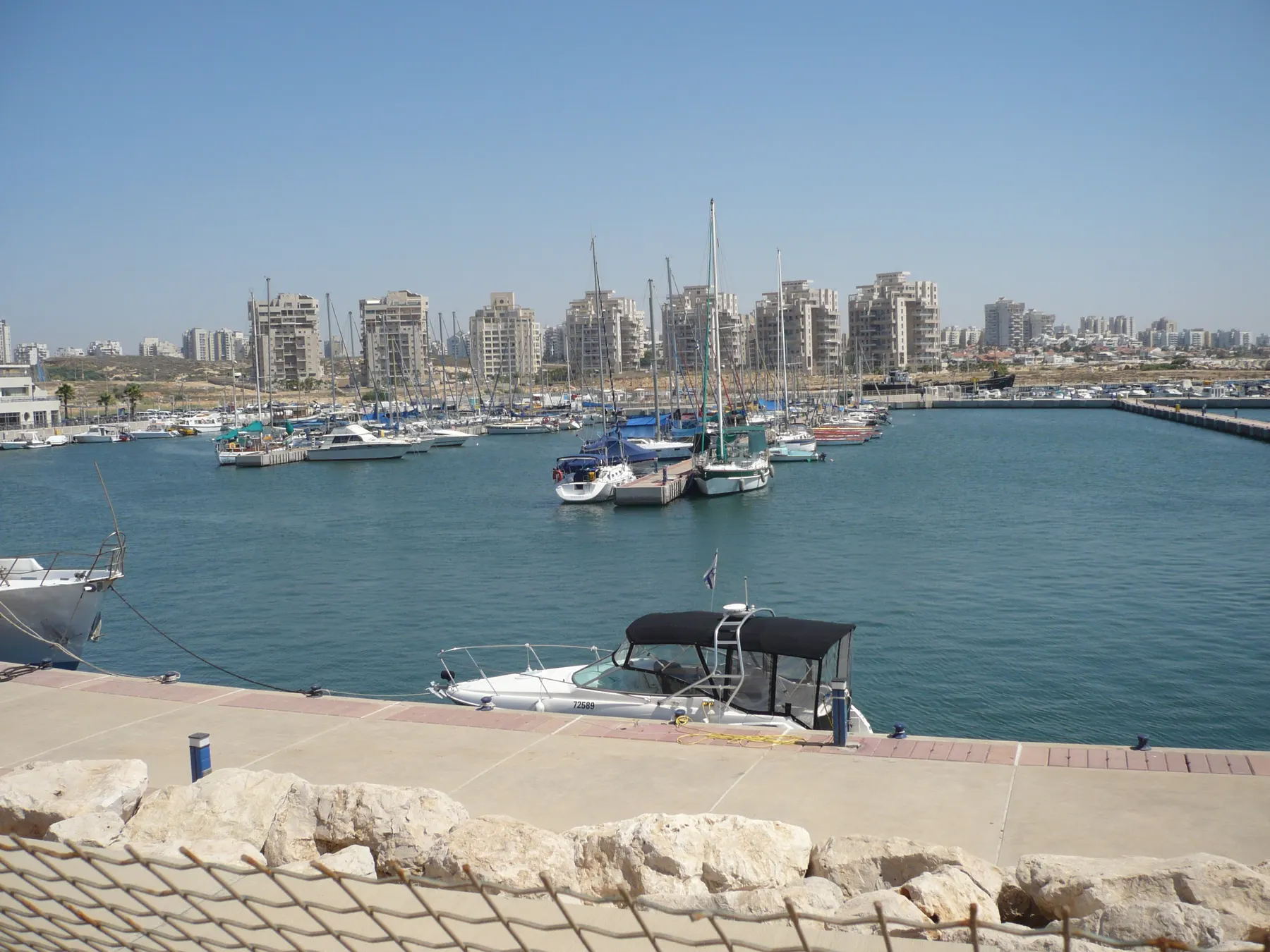 Yachts and motorboats moored in Ashdod Marina, with the city's apartment towers behind the water