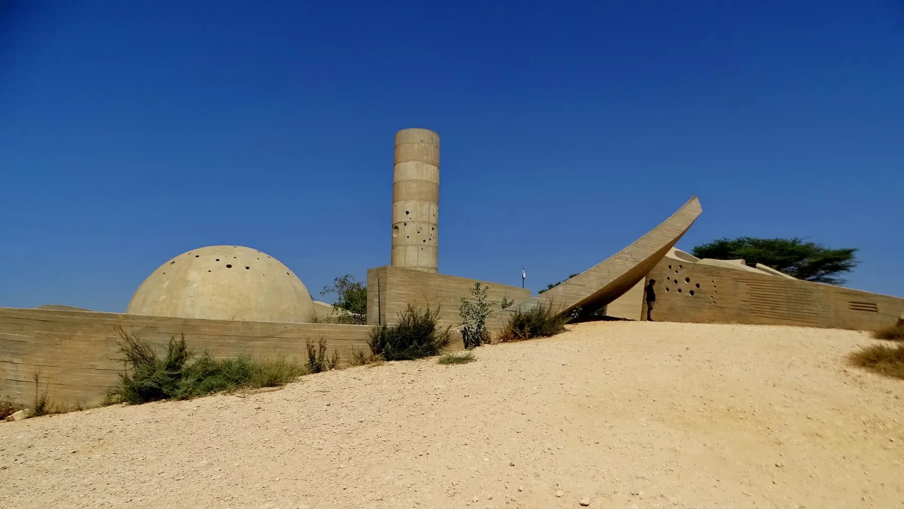 The Negev Brigade Monument on a desert hill above Beer Sheva: a concrete tower, a dome and a sloping wall under a blue sky
