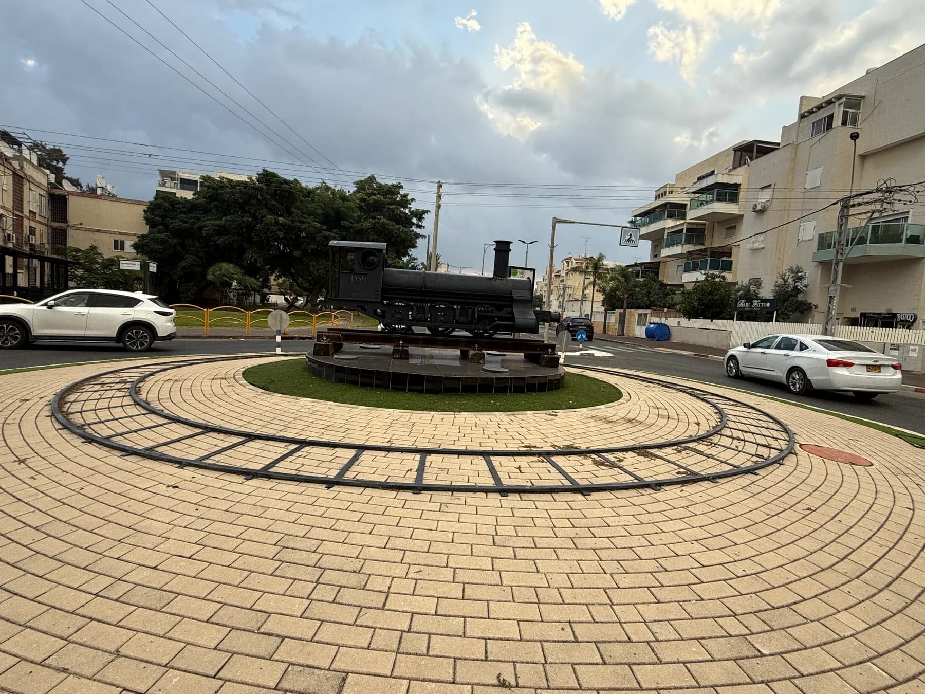 A roundabout near the railway station in Kiryat Motzkin, with a steam locomotive sculpture on a ring of rails.