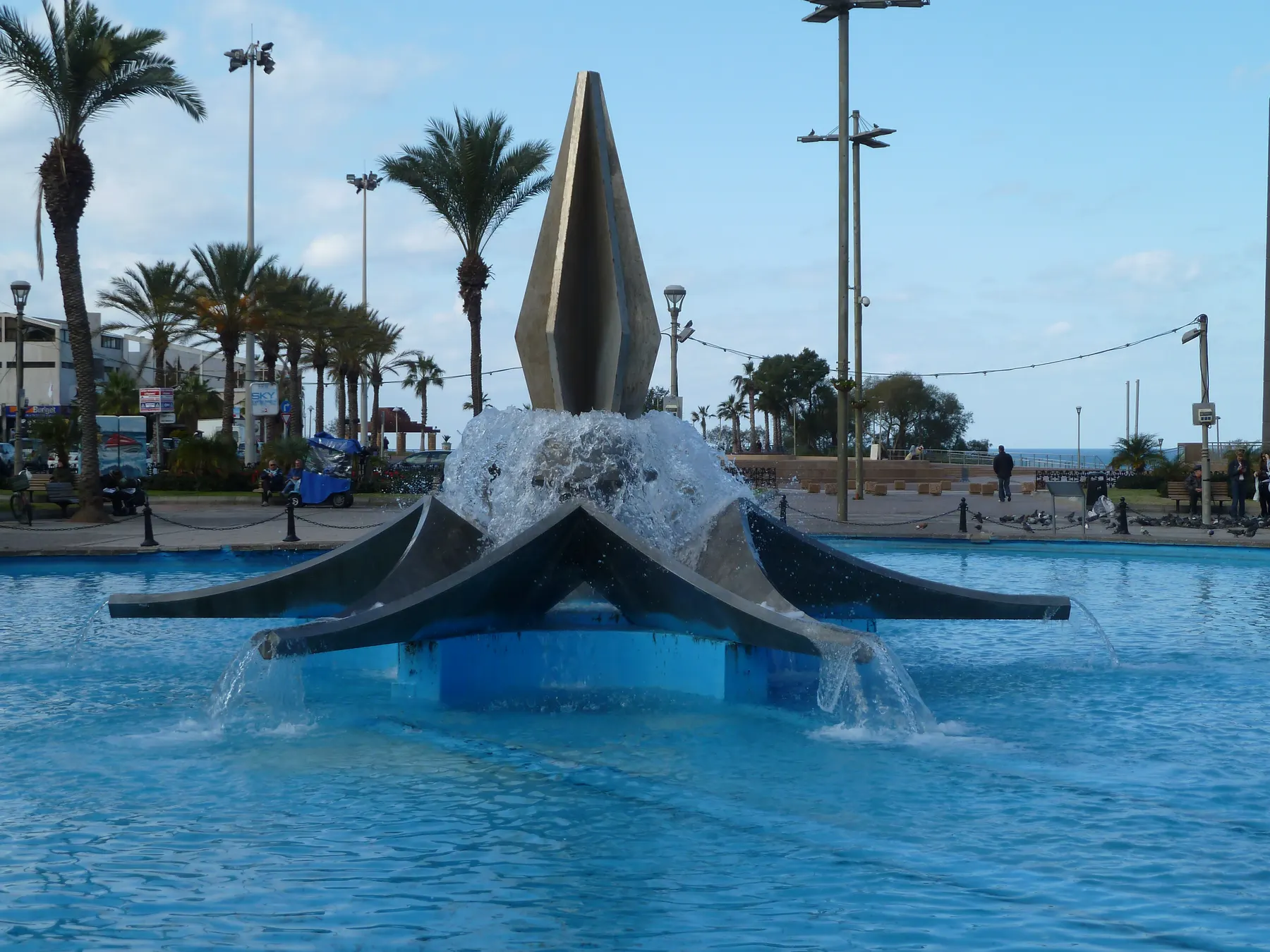 The fountain in Ha'atzmaut Square in the centre of Netanya, with palm trees and the sea behind it