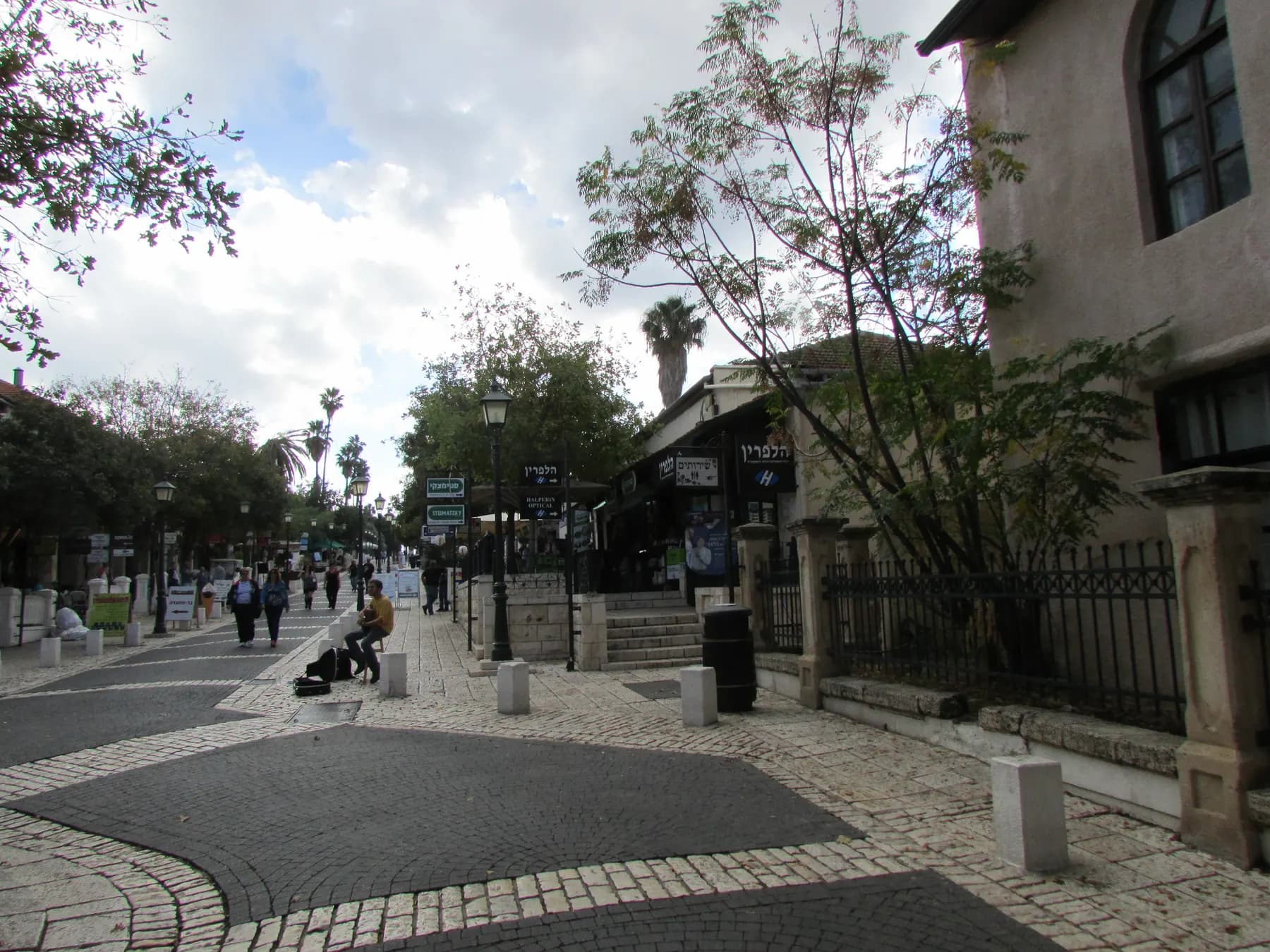 The stone-paved pedestrian street of Zichron Yaakov, with an old stone house, iron railings and street lamps