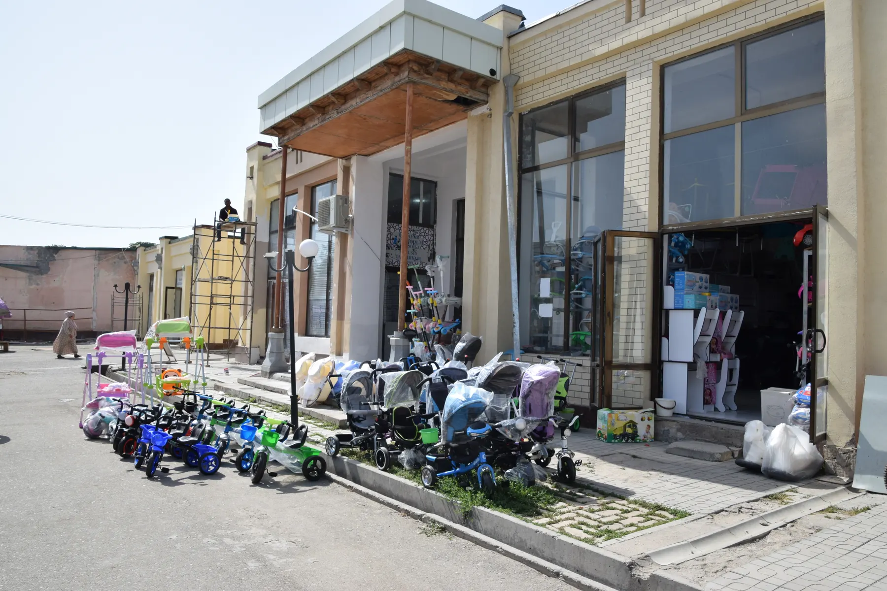 Prams and children's ride-on toys lined up outside a baby shop.
