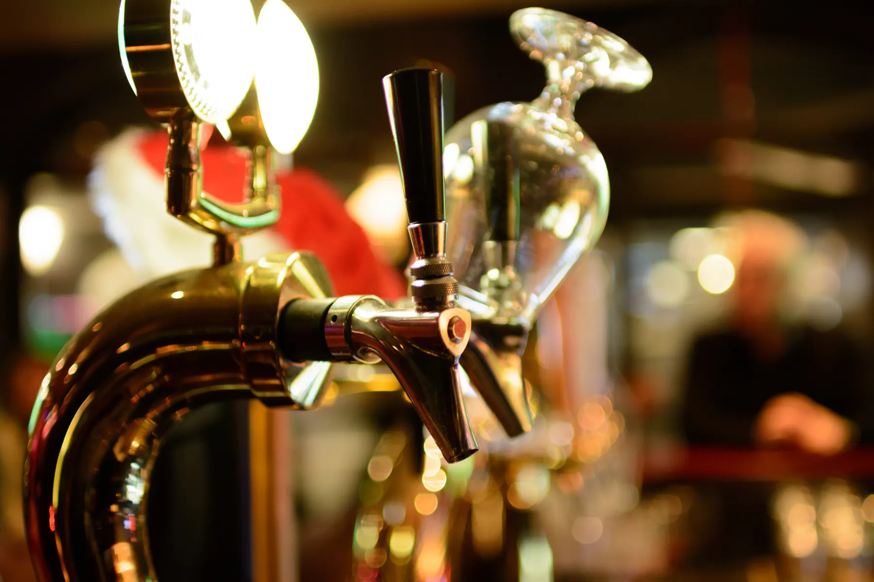A chrome beer tap at a bar, with an upturned glass beside it