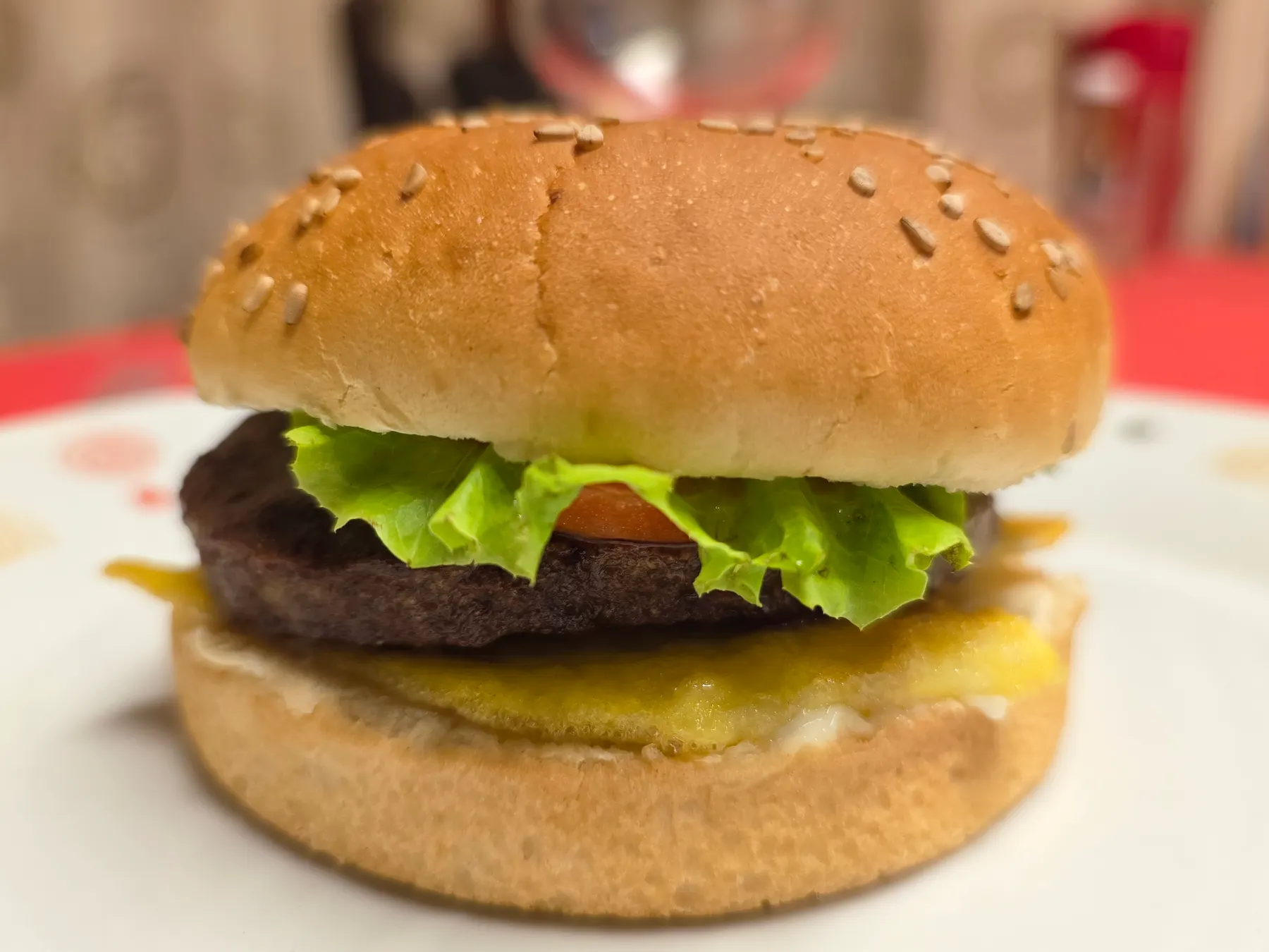 A beef burger with cheese and lettuce in a sesame bun