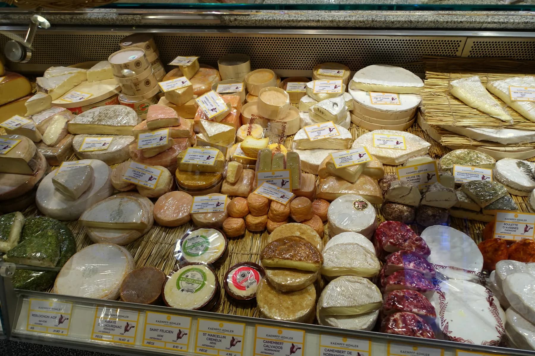 A cheese counter full of soft and hard cheeses, each with its label.