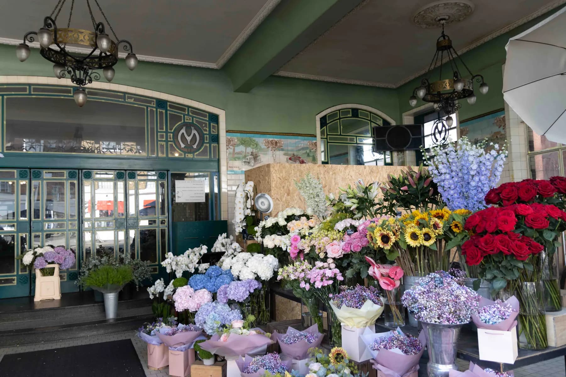 Buckets of cut flowers, sunflowers and roses at a florist's stall.