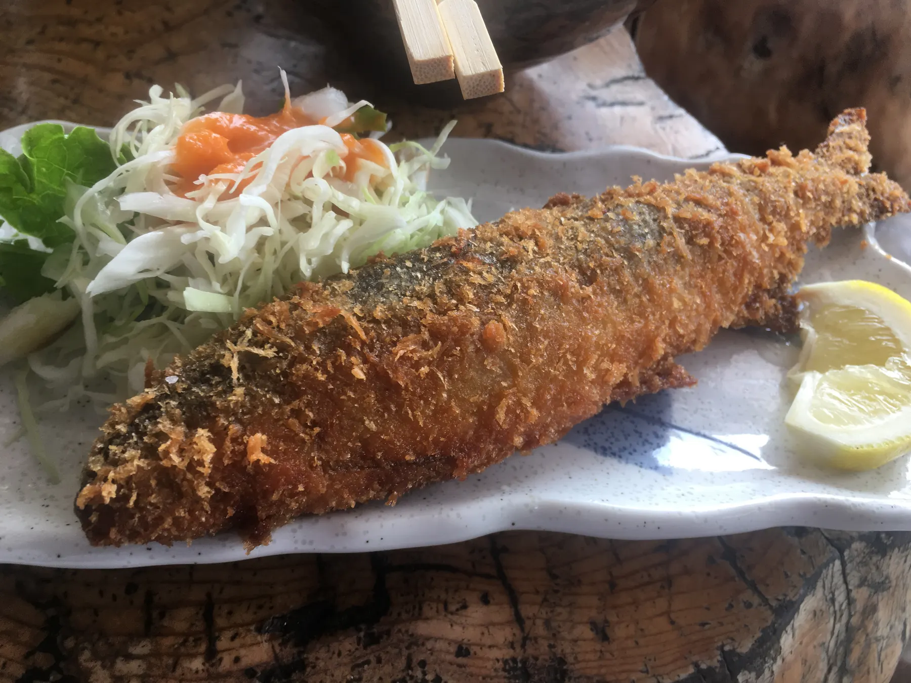 A crispy breaded fried fish with lemon and a salad
