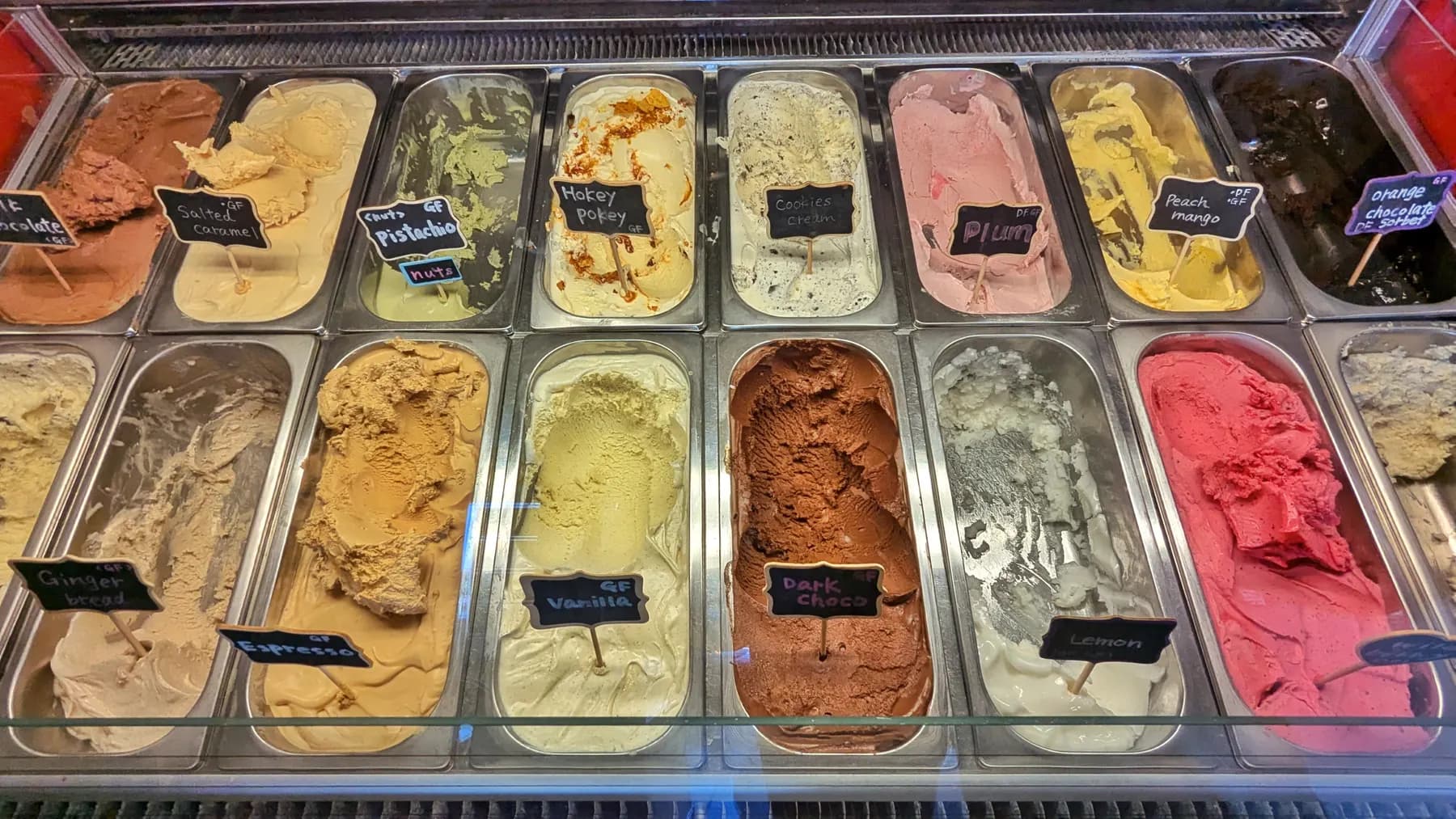 Trays of gelato in a shop's display counter, each flavour on a chalk label
