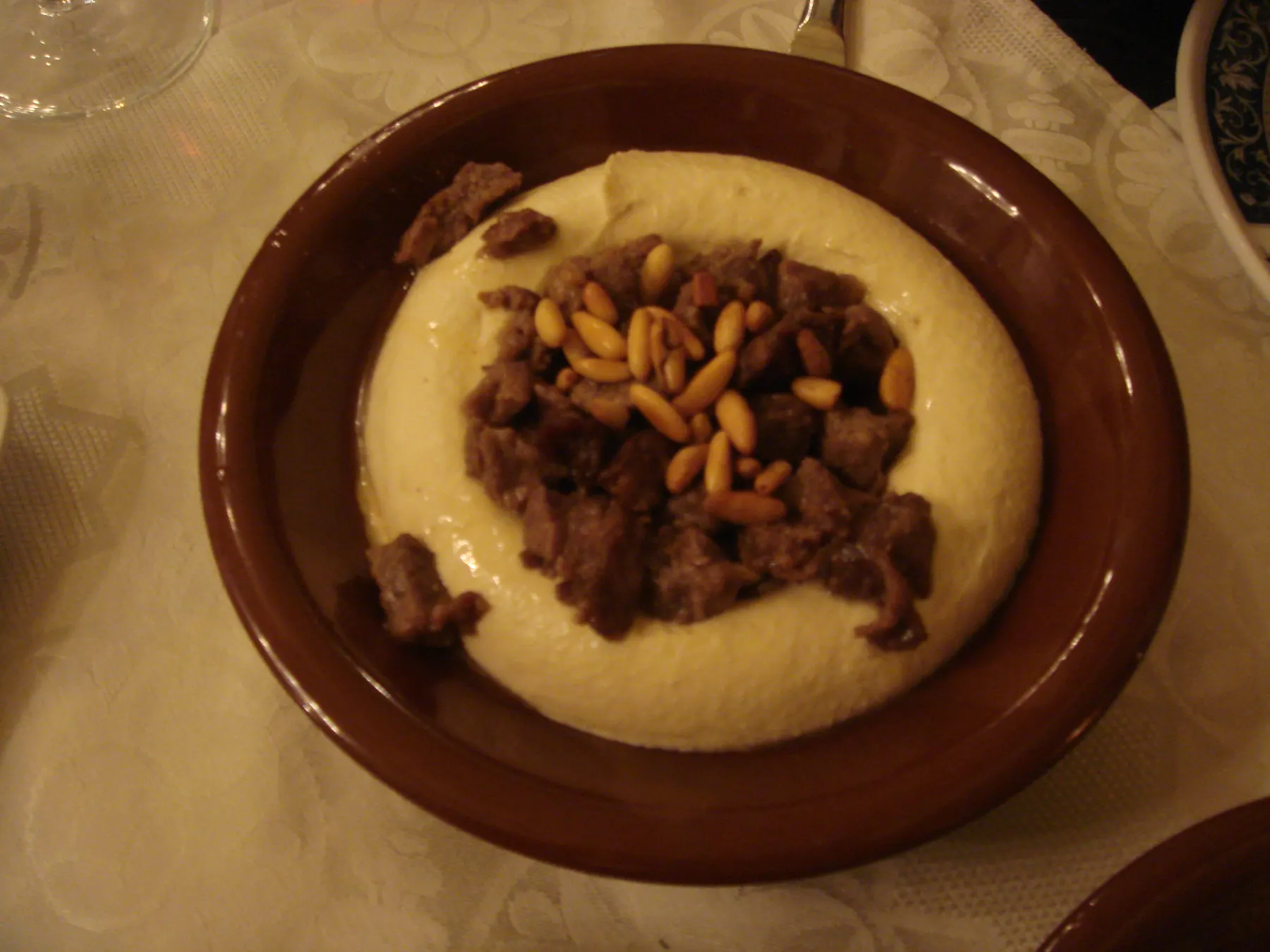 A bowl of hummus topped with fried minced meat and pine nuts
