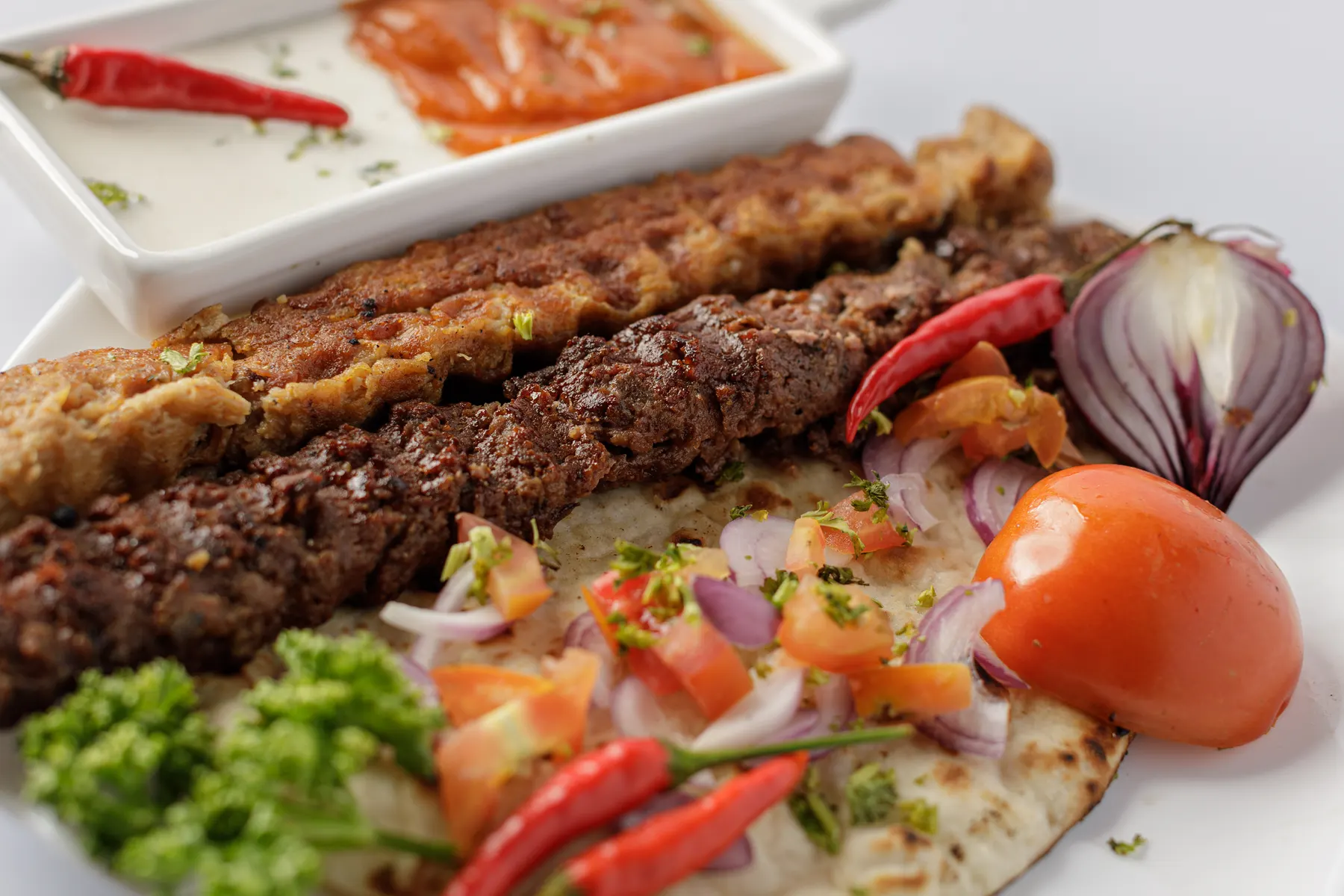 Grilled beef and chicken kebabs on a pita, with salad and chillies