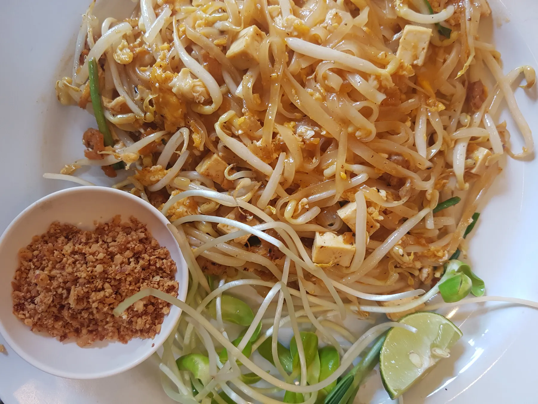 Pad thai with tofu and bean sprouts, with crushed peanuts and lime on the side