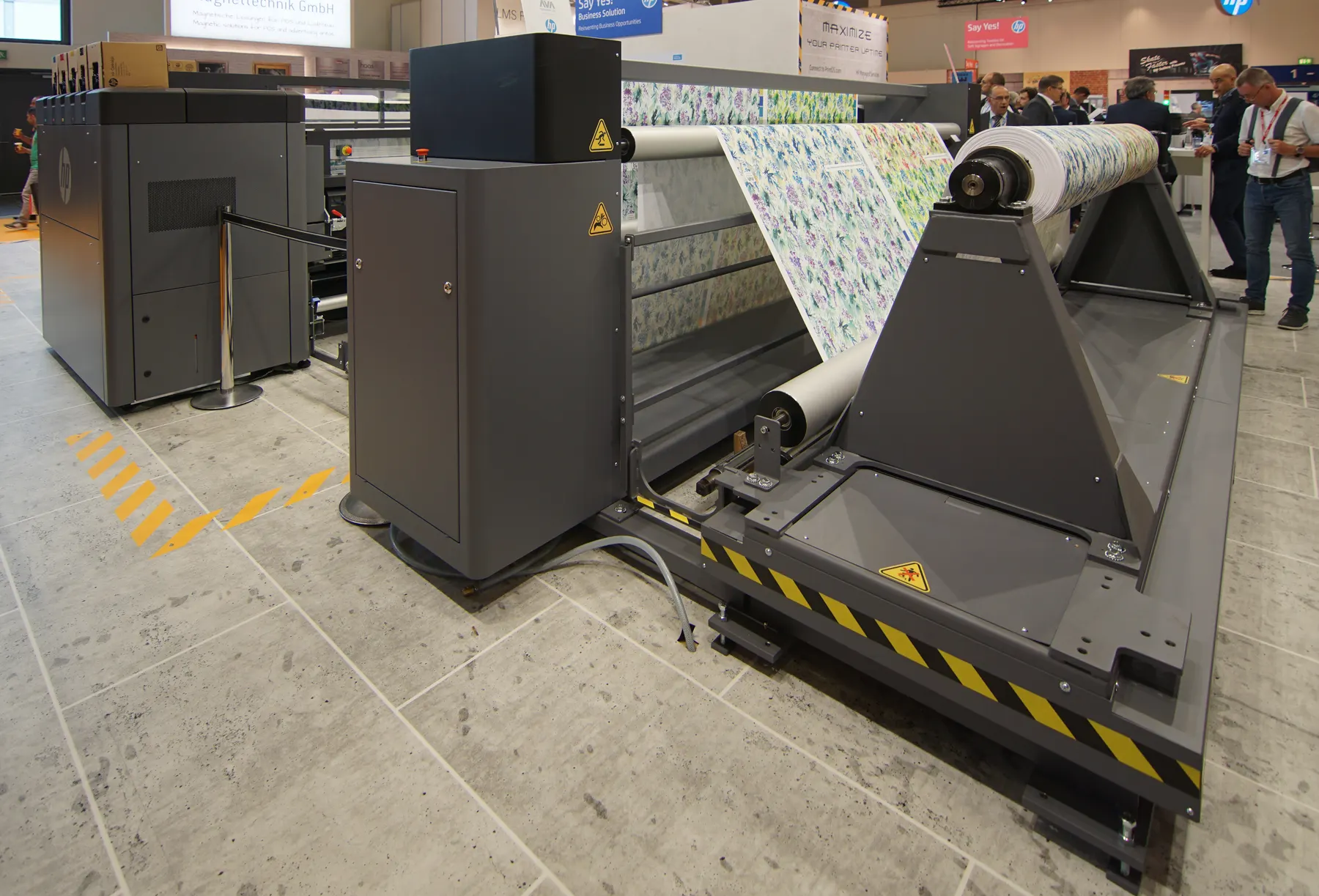 A wide-format printer feeding a roll of printed fabric.