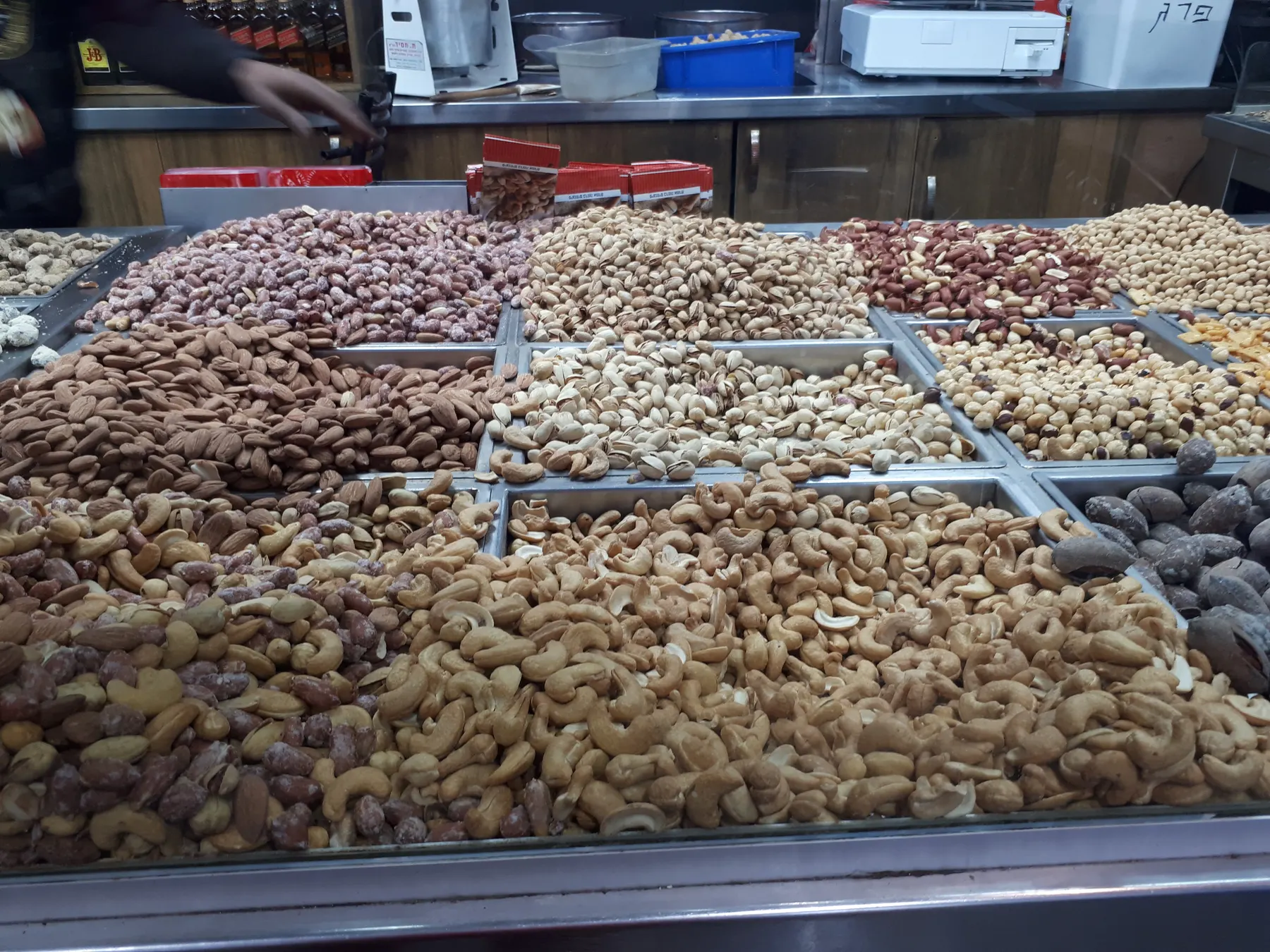 Trays of roasted nuts at a market stall: cashews, almonds, pistachios and peanuts.