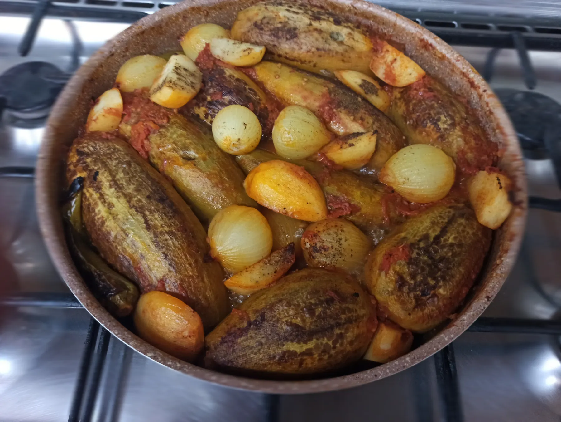 A pot of stuffed aubergines with onions and potatoes in tomato sauce