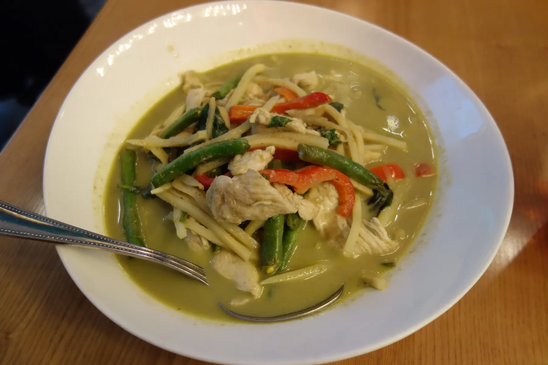 A bowl of Thai green curry with chicken, bamboo shoots and basil
