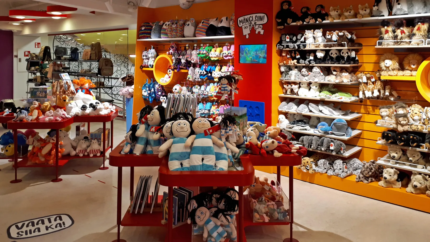 Soft toys and dolls on shelves in a toy shop.