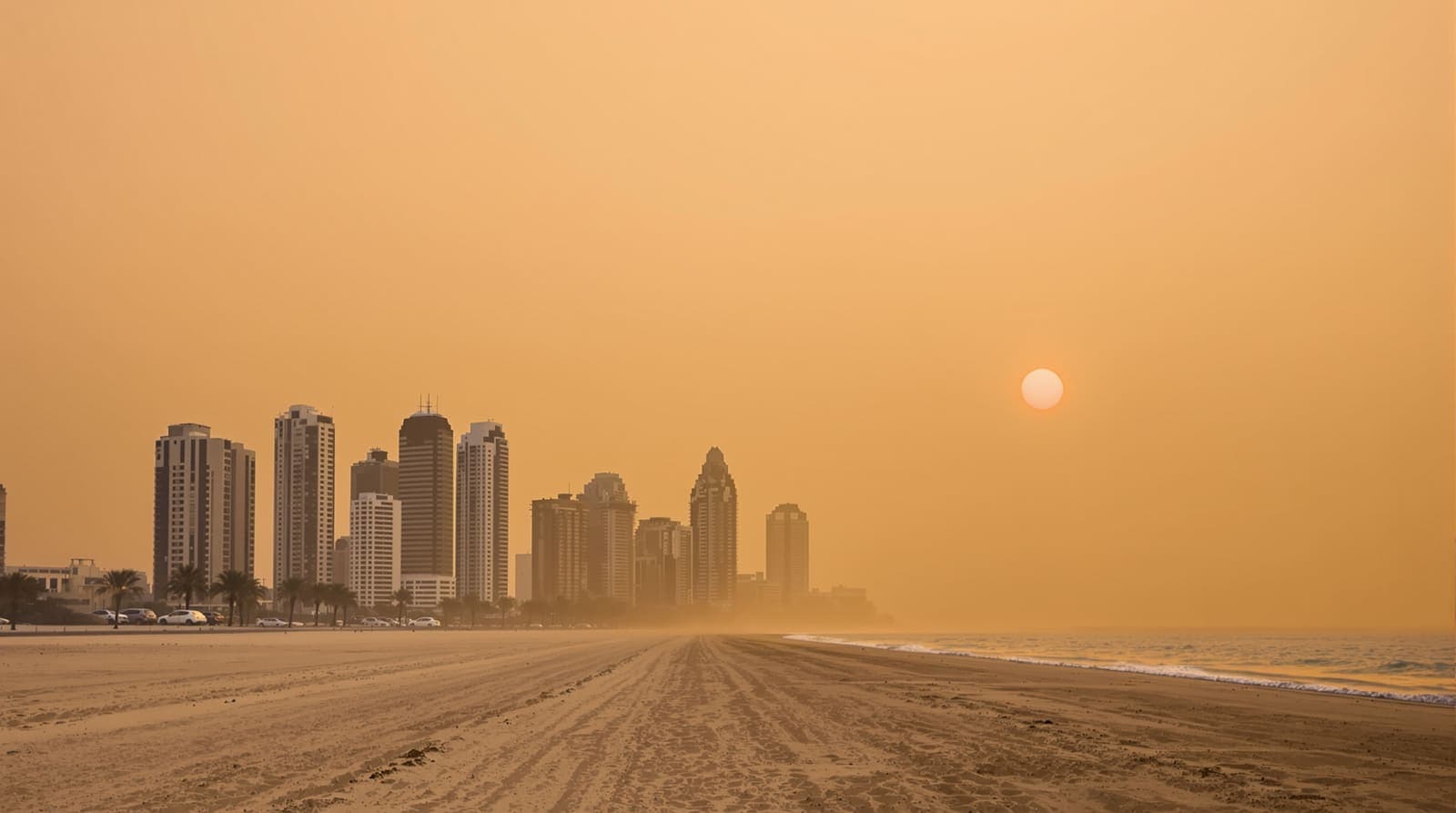 Illustration of a city skyline and beach shrouded in dense orange desert dust haze under a dimmed sun.
