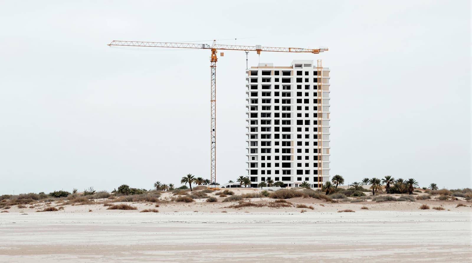 Illustration of a single half-built resort tower and an idle crane on scrubland behind a beach on the Cyprus coast.