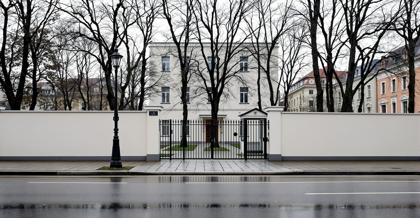 Illustration of a quiet Belgrade street at dawn with a pale embassy building behind a tall steel security fence and closed gate.