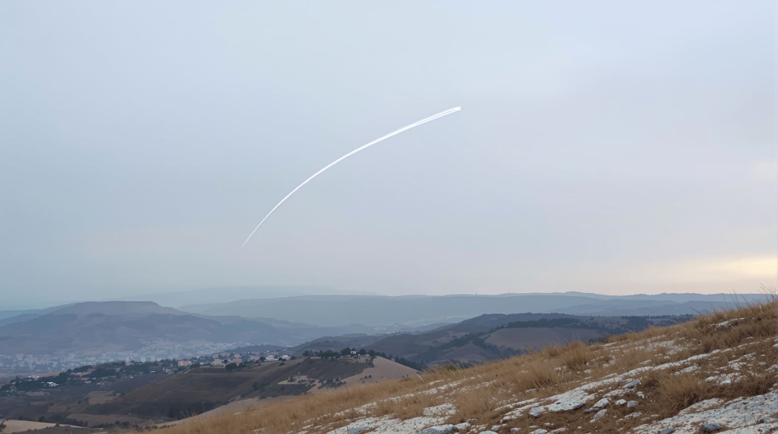 Illustration of a thin white contrail arcing over quiet terraced hills and distant stone villages in southern Lebanon at dusk.