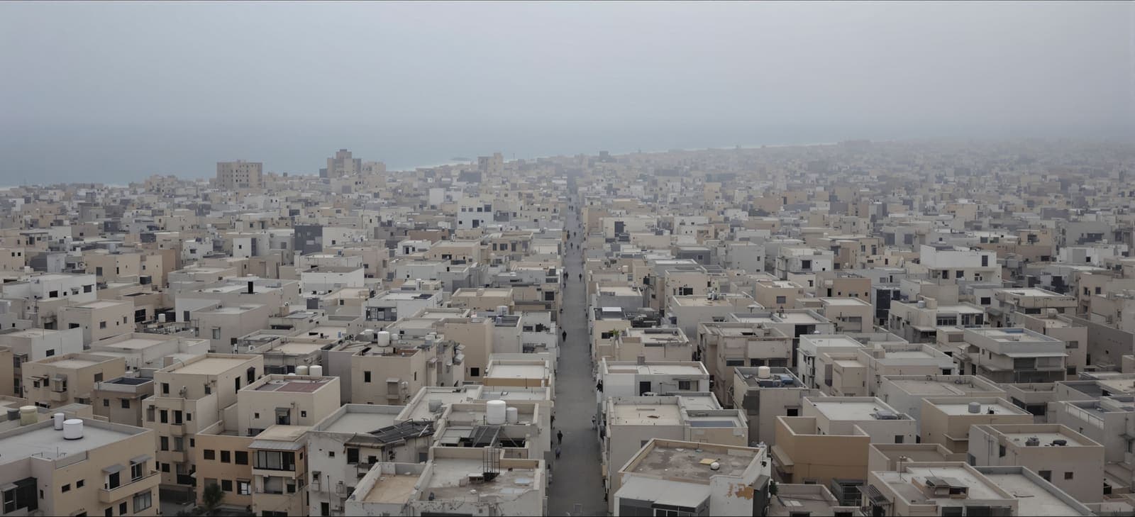 Illustration of densely packed concrete rooftops in a central Gaza camp district seen from above at an overcast dawn.