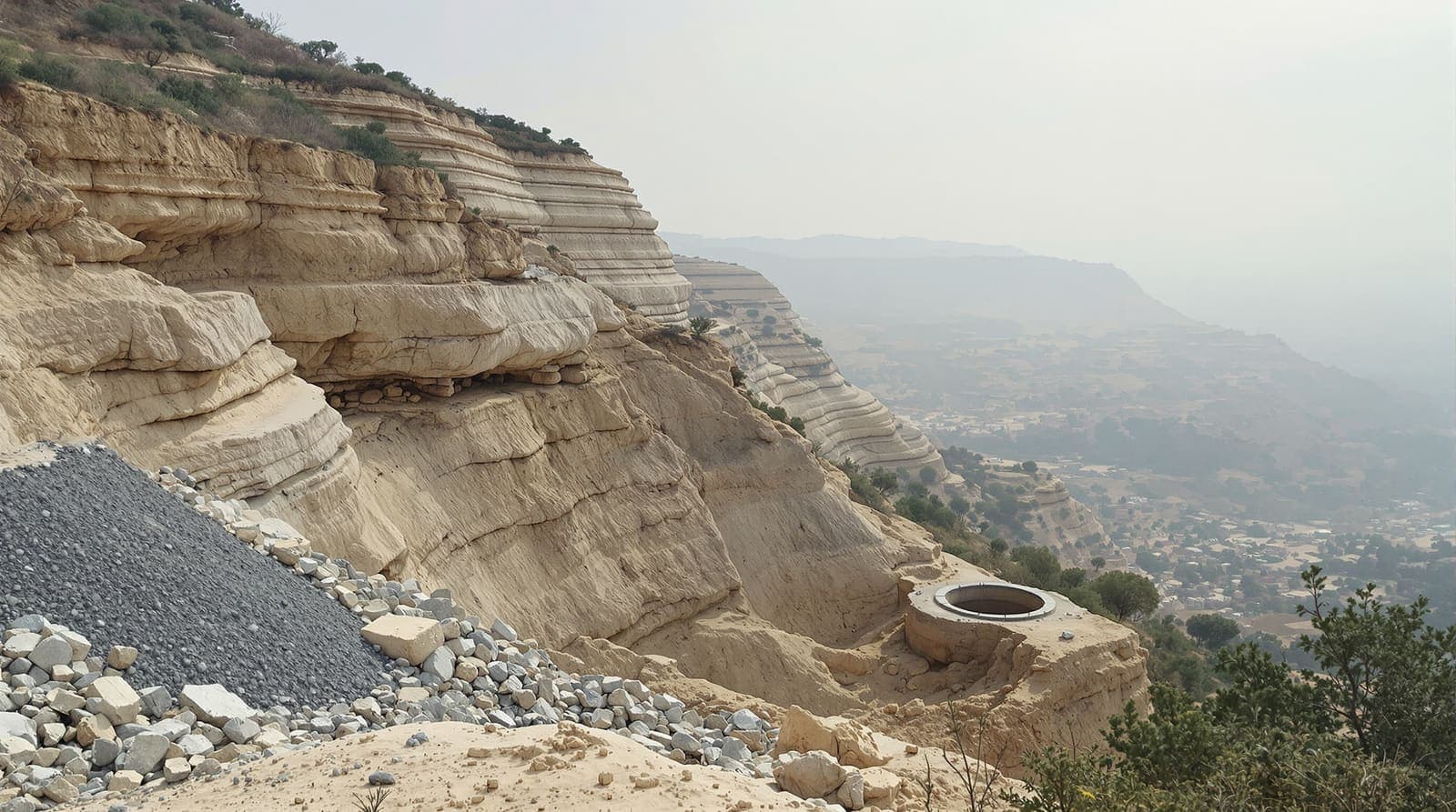 Illustration of a limestone ridgeline in southern Lebanon at dawn with a collapsed excavated shaft mouth in the stony foreground.