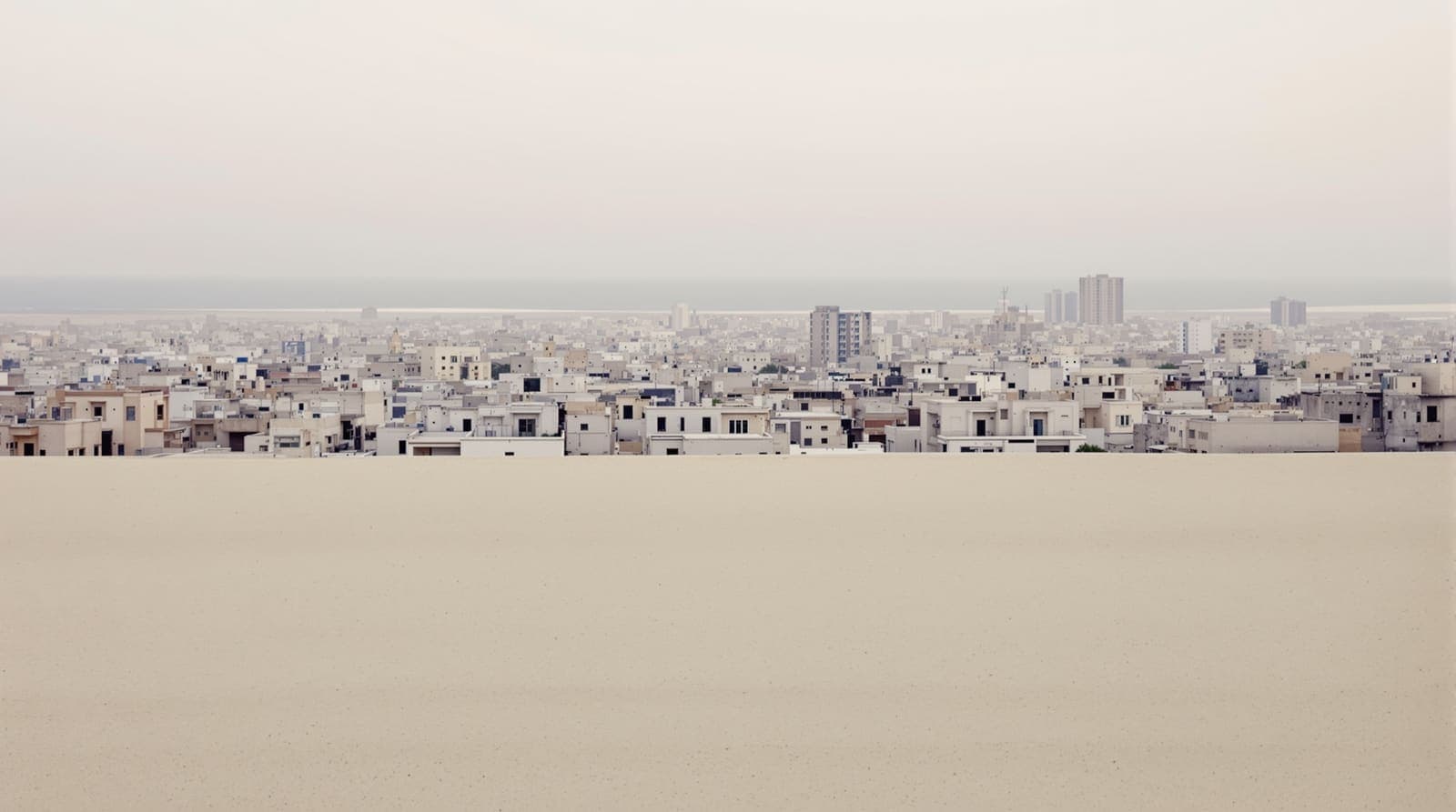 Illustration of the Gaza City skyline seen from a distance in hazy dawn light across flat sandy farmland.