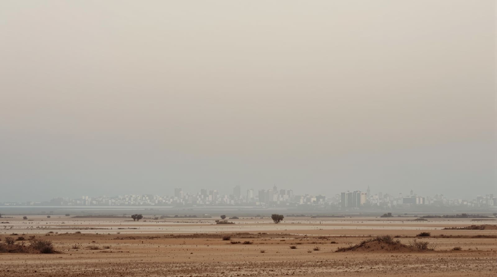 Illustration of the Gaza City skyline seen from a distance across sandy fields in hazy dawn light.