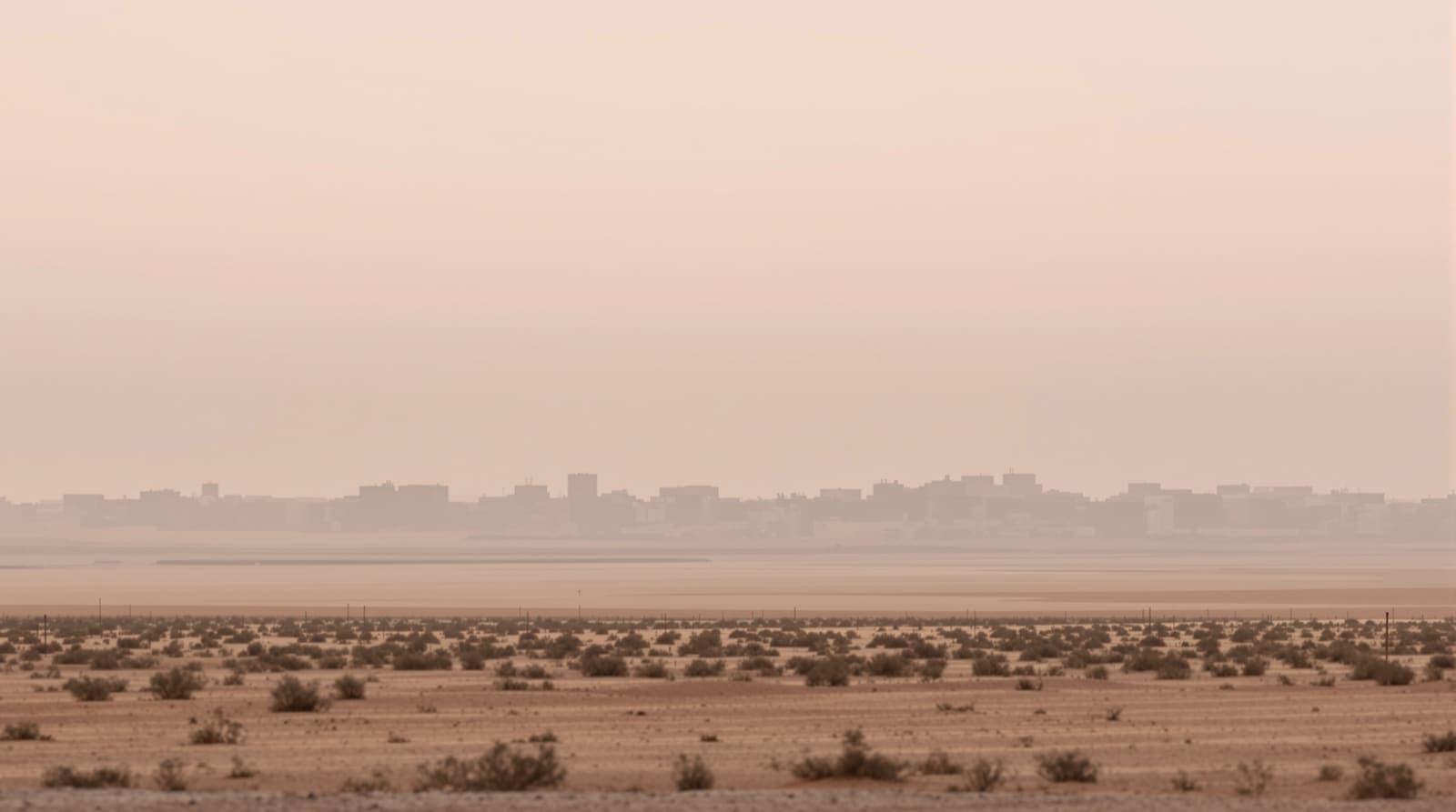 Illustration of the low, hazy skyline of Khan Younis in southern Gaza seen at dawn from across flat sandy farmland.