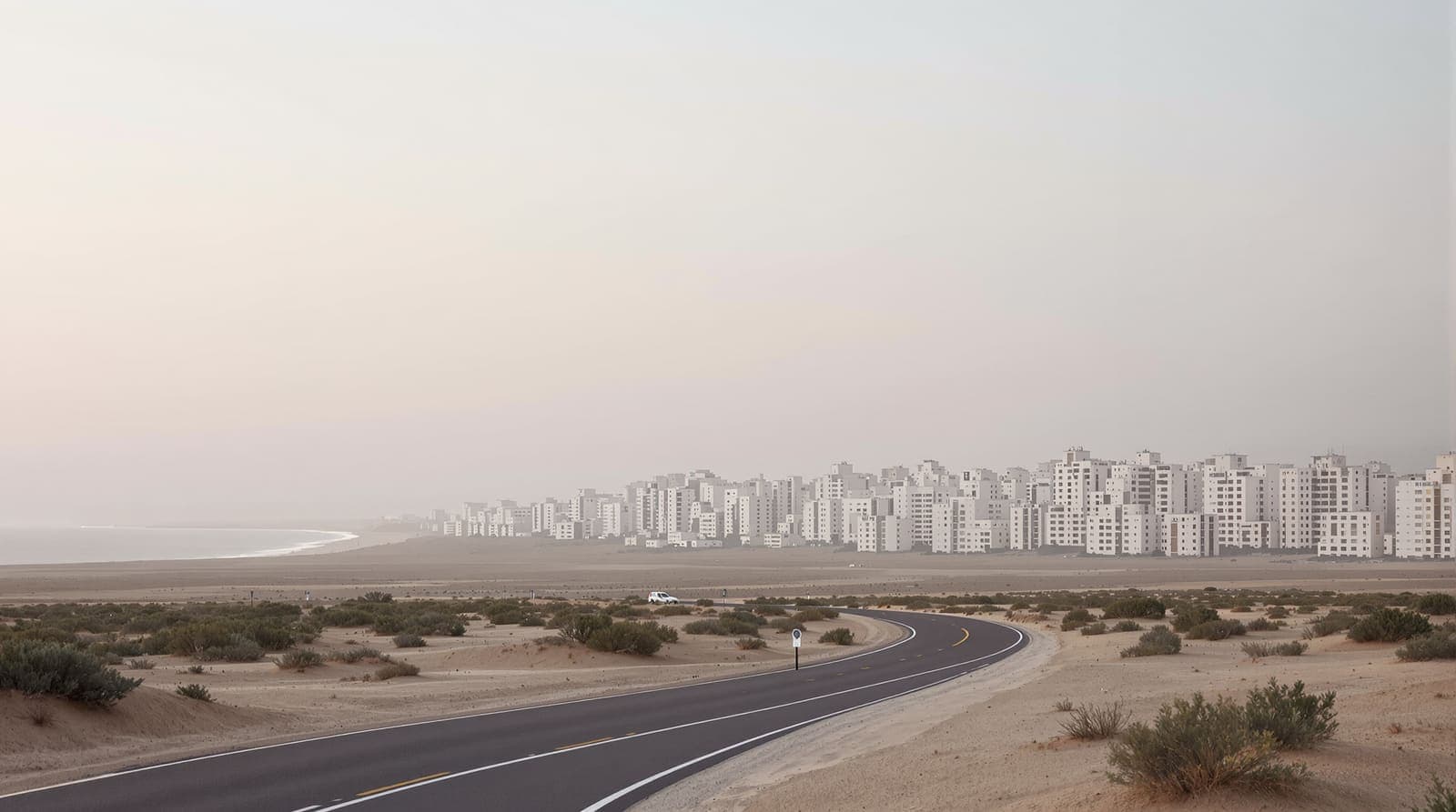 Illustration of a distant coastal city skyline at dawn, seen across open sandy ground with a quiet empty road in the foreground.