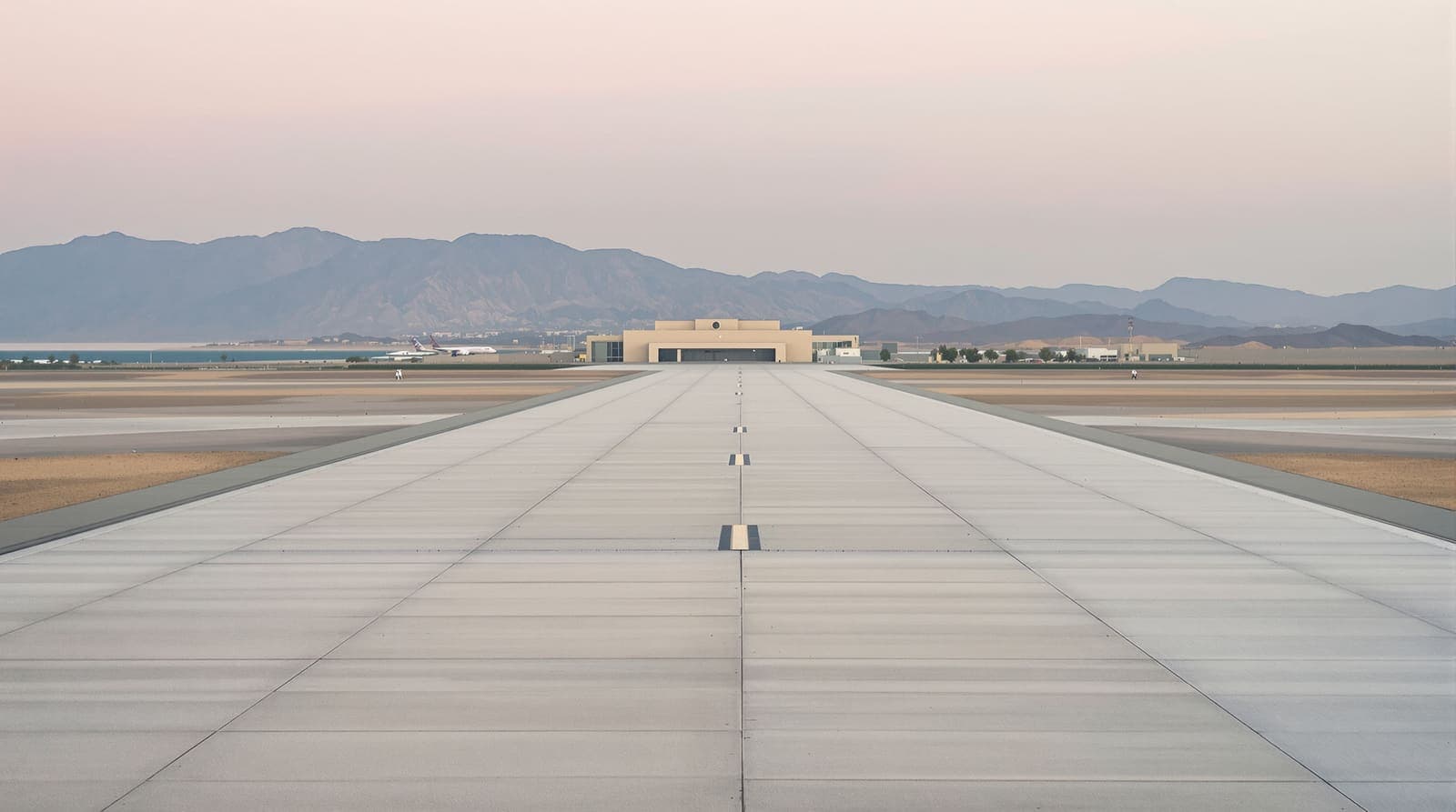 Illustration of an empty airport runway in Aden at dawn, with volcanic ridges and the harbour in the hazy distance.