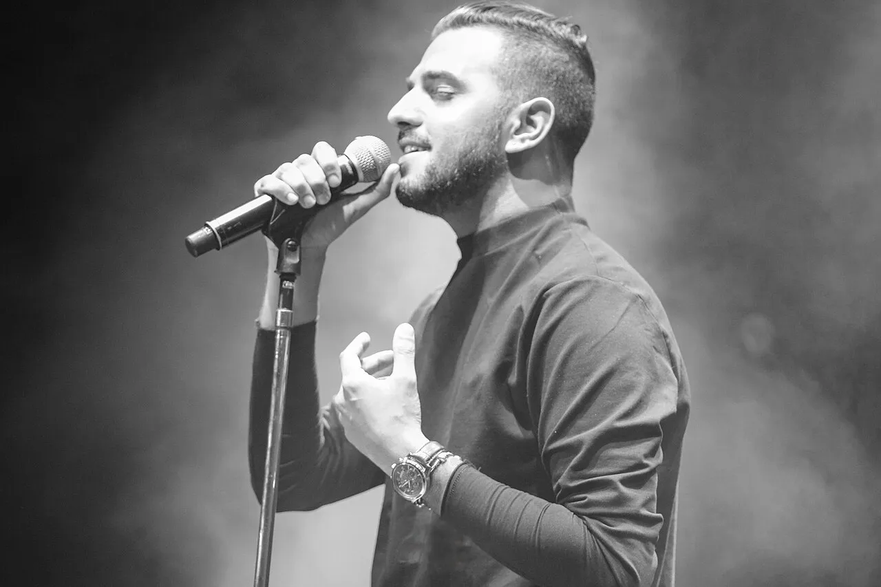 Itay Levi singing into a microphone on stage in Caesarea, in black and white, 2015