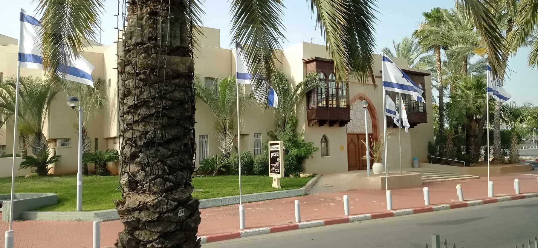 The Babylonian Jewry Heritage Center in Or Yehuda, behind palm trees and flags