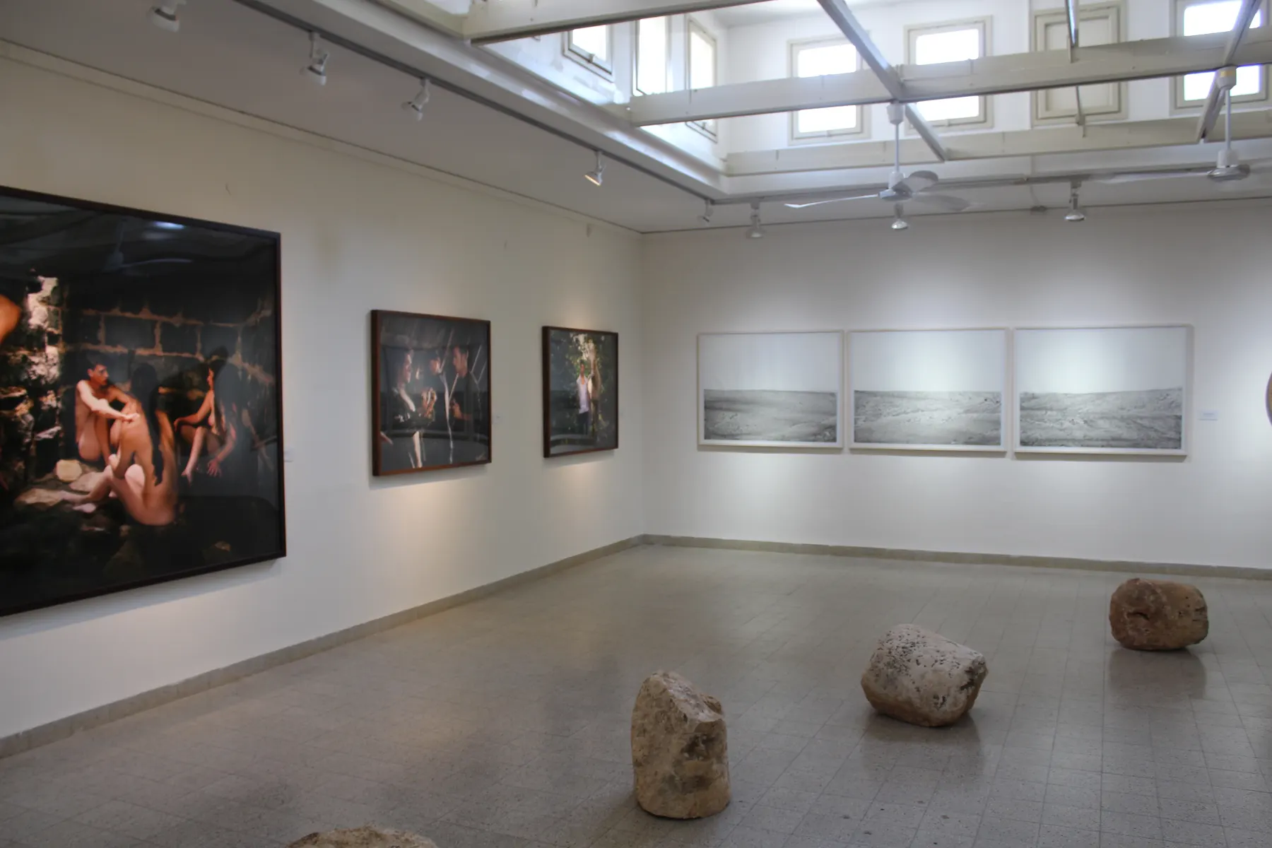 A gallery hall at Beit Sturman, with photographs on the walls and stones on the floor